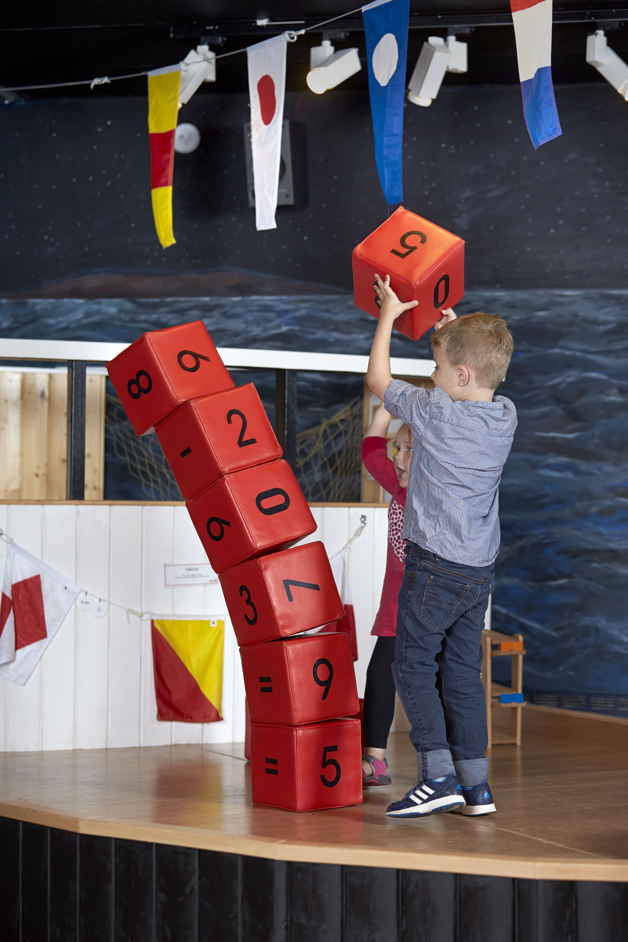 En liten kille som staplar röda stora klossar.