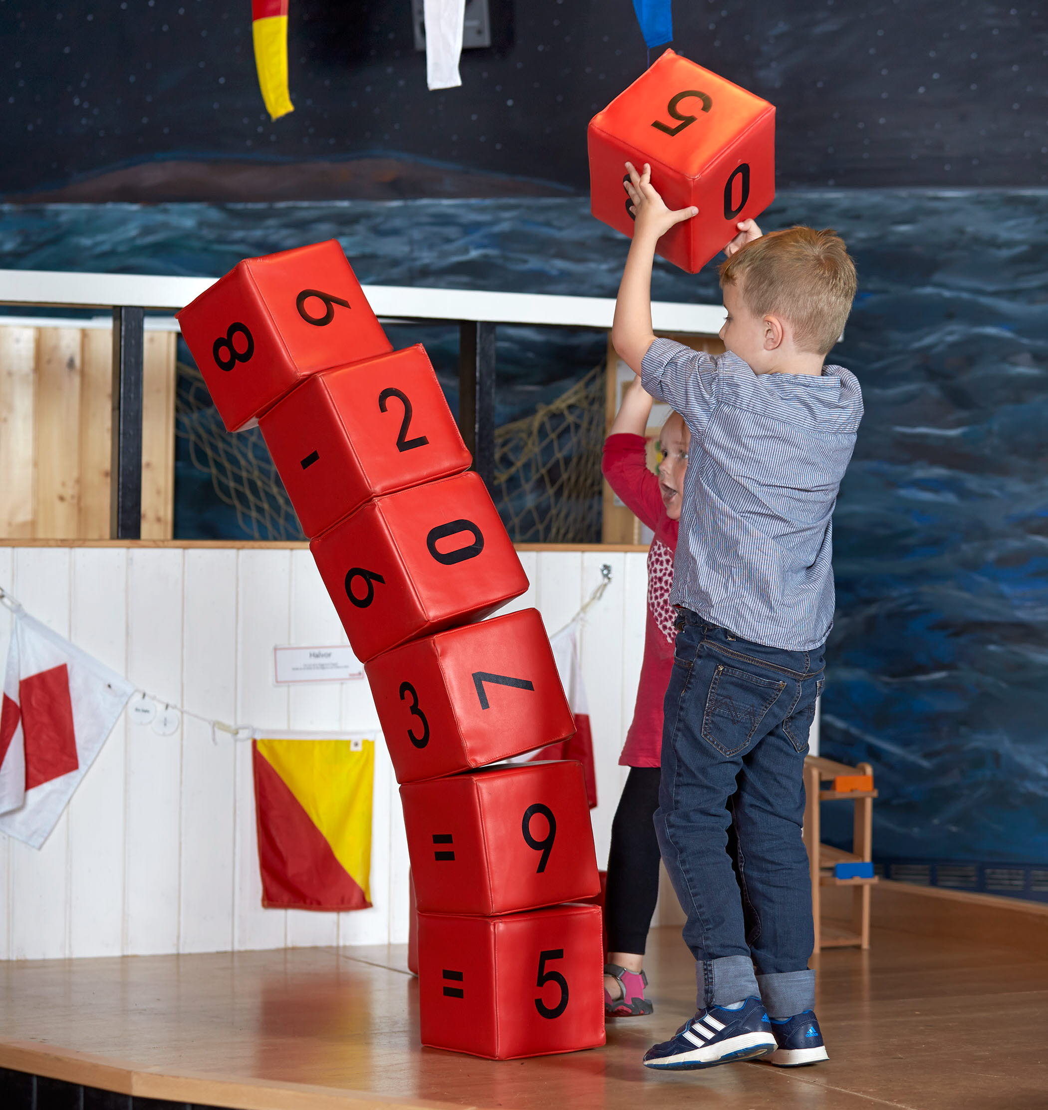 En liten kille som staplar röda stora klossar.