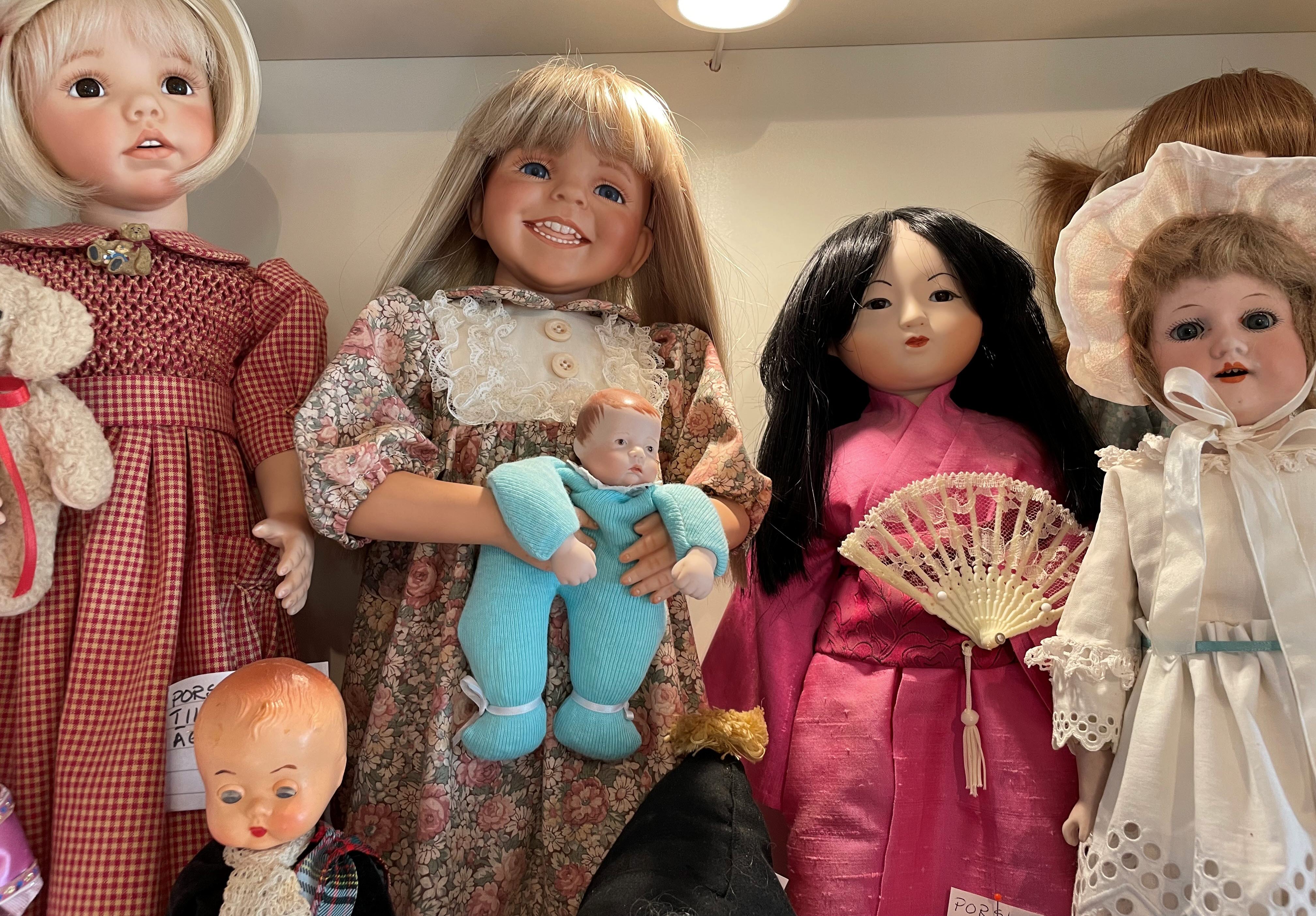 Flera dockor på rad med olika kläder och utseende.