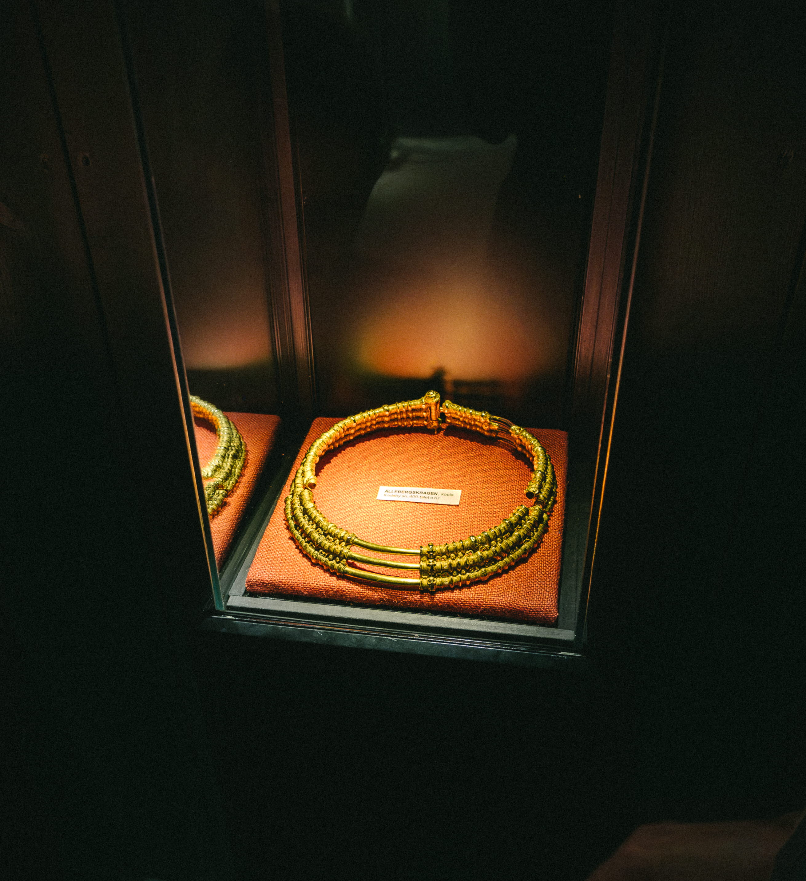 Ett barn och en kvinna som tittar på en guldkrage, det är mörkt i rummet men kragen är upplyst.