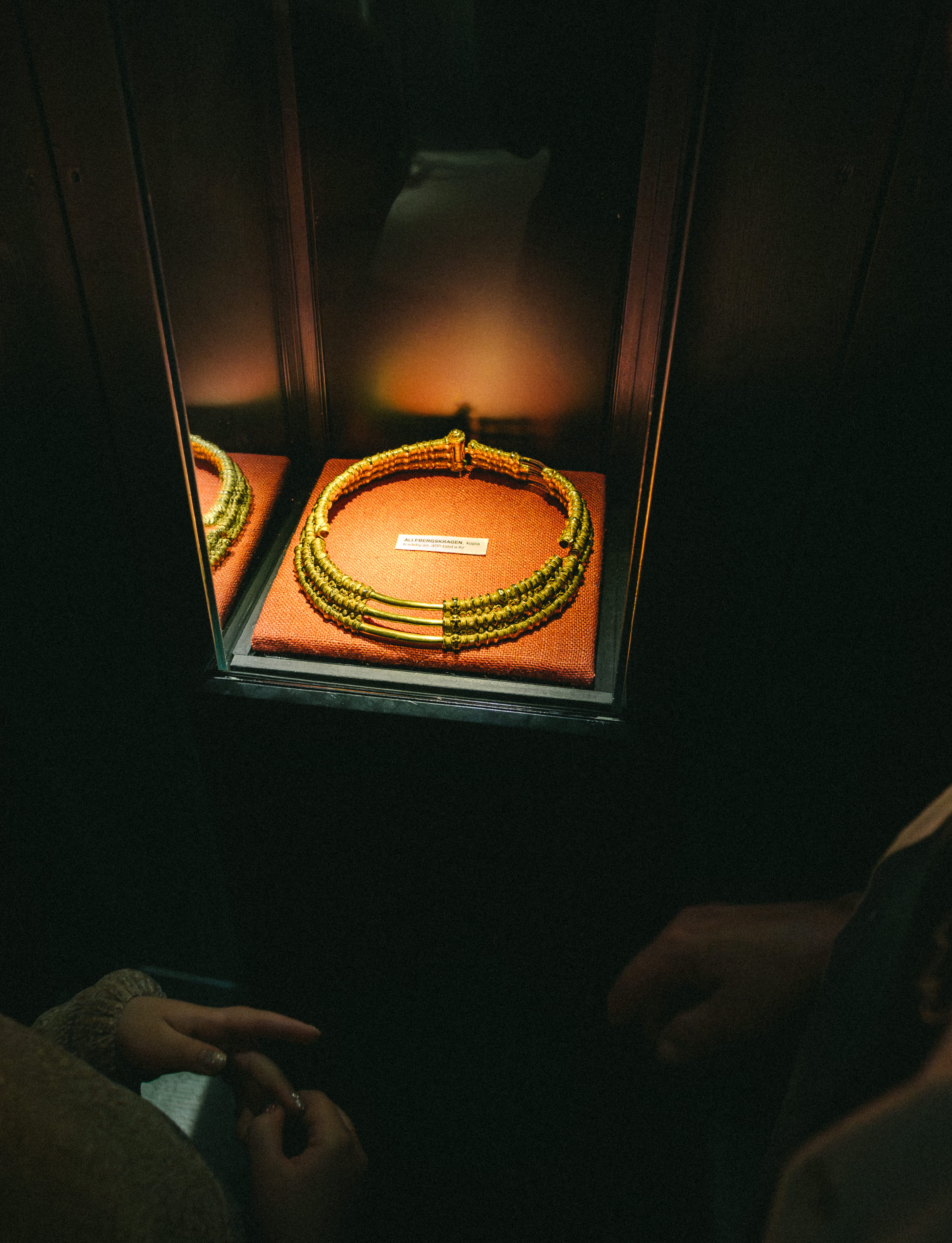 Ett barn och en kvinna som tittar på en guldkrage, det är mörkt i rummet men kragen är upplyst.