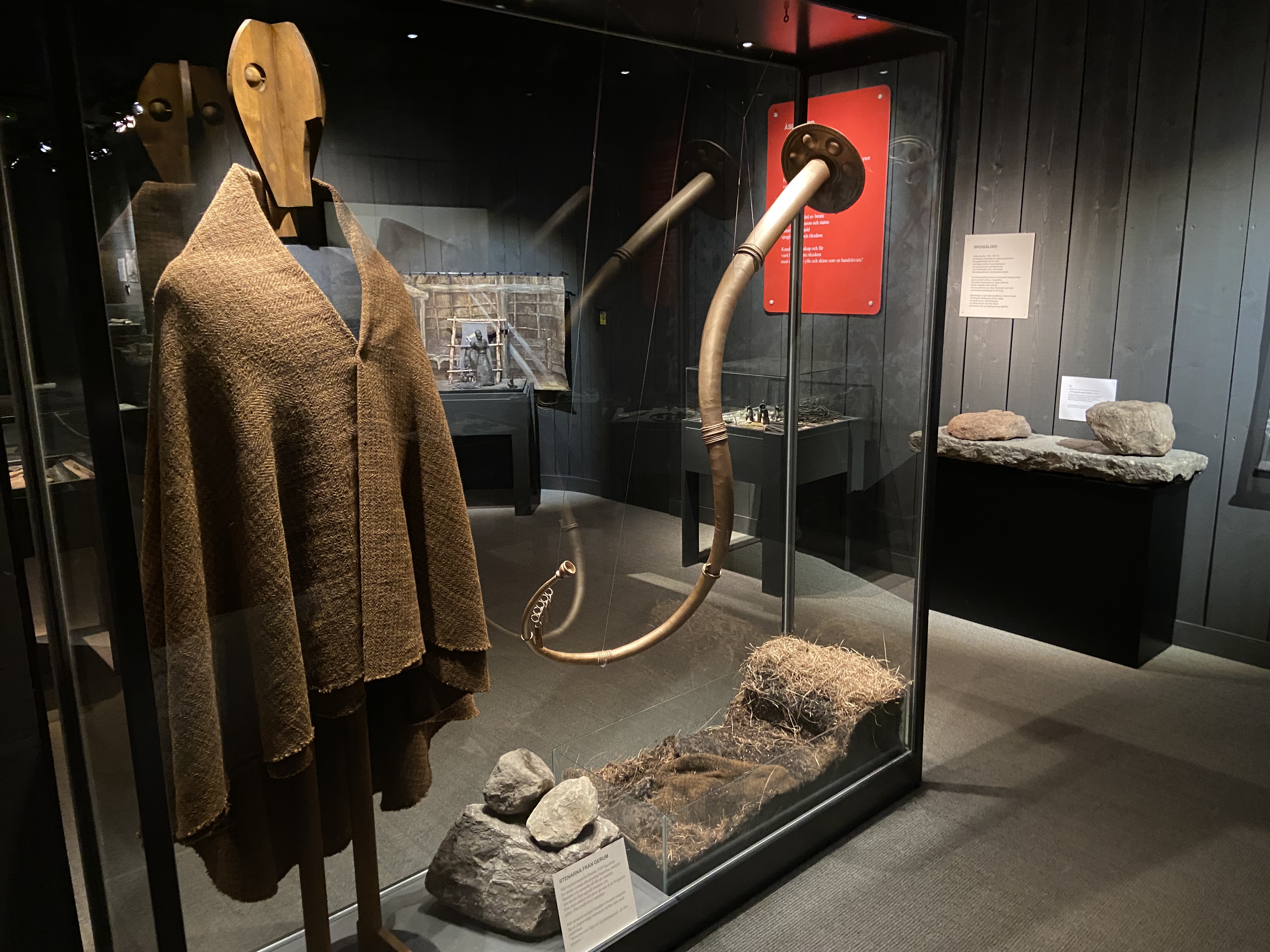 Stor glasmonter med en trädocka som bär en mantel. Bredvid hänger en lur i metall.