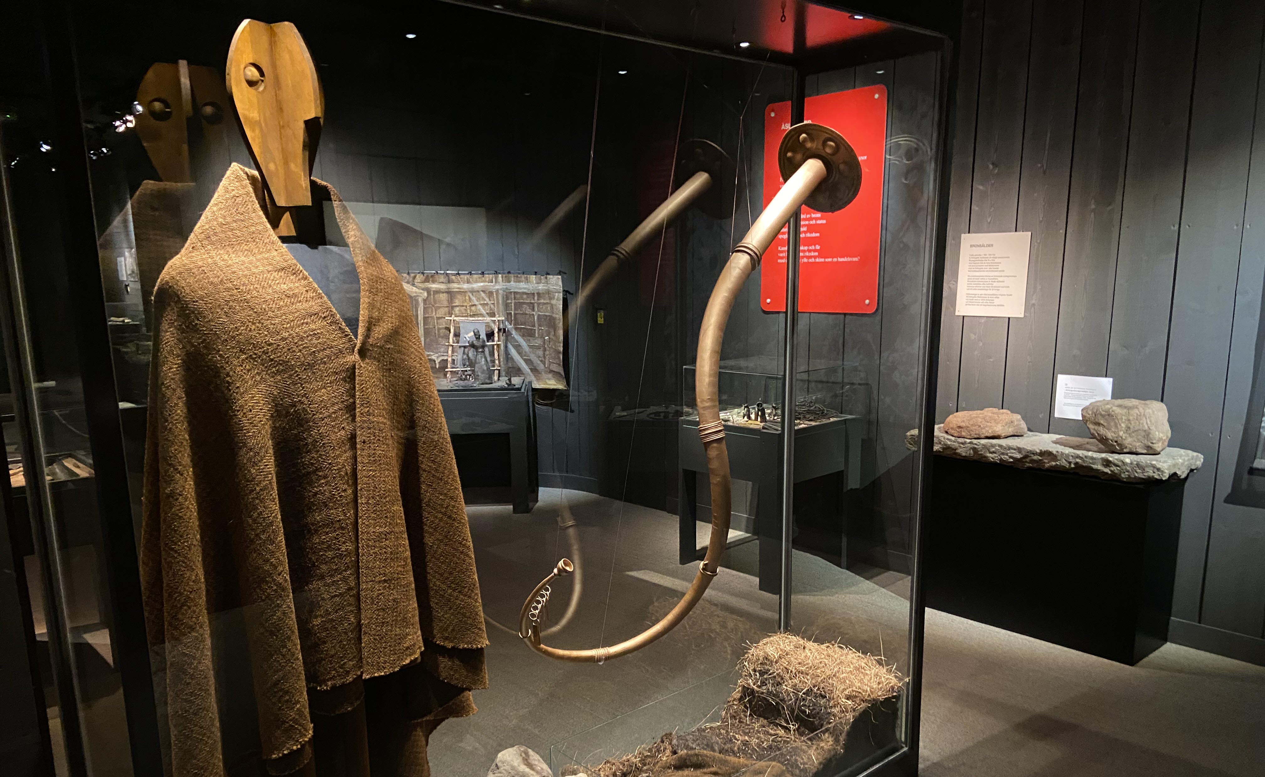 Stor glasmonter med en trädocka som bär en mantel. Bredvid hänger en lur i metall.