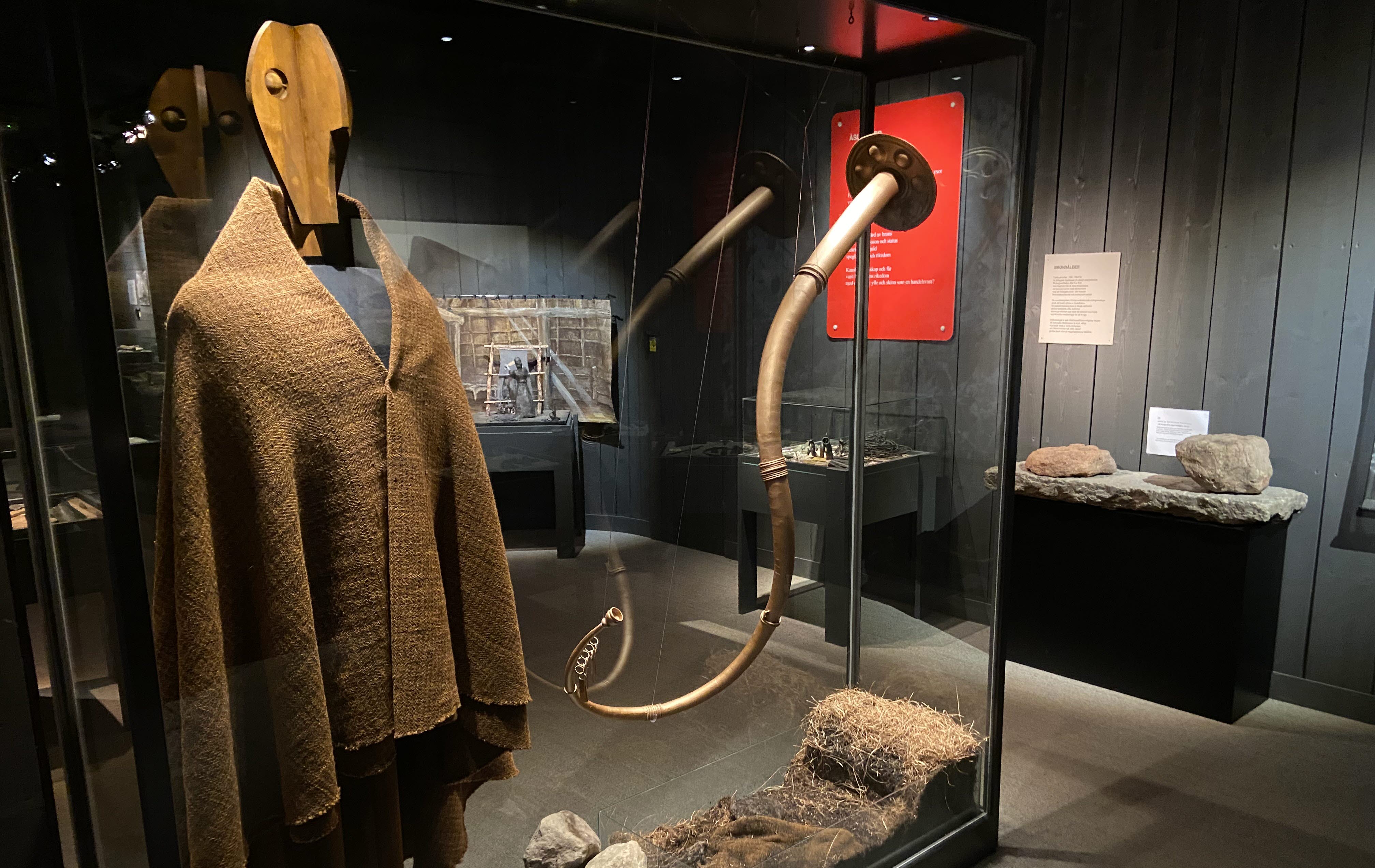 Stor glasmonter med en trädocka som bär en mantel. Bredvid hänger en lur i metall.