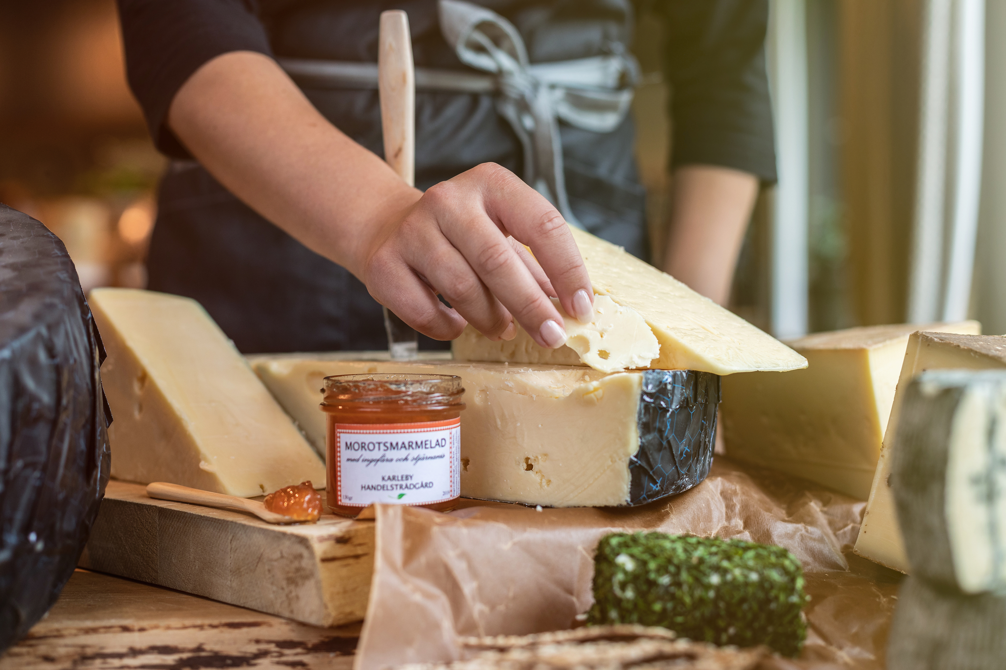 Olika ostar och marmelad. En hand som tar en ostbit.