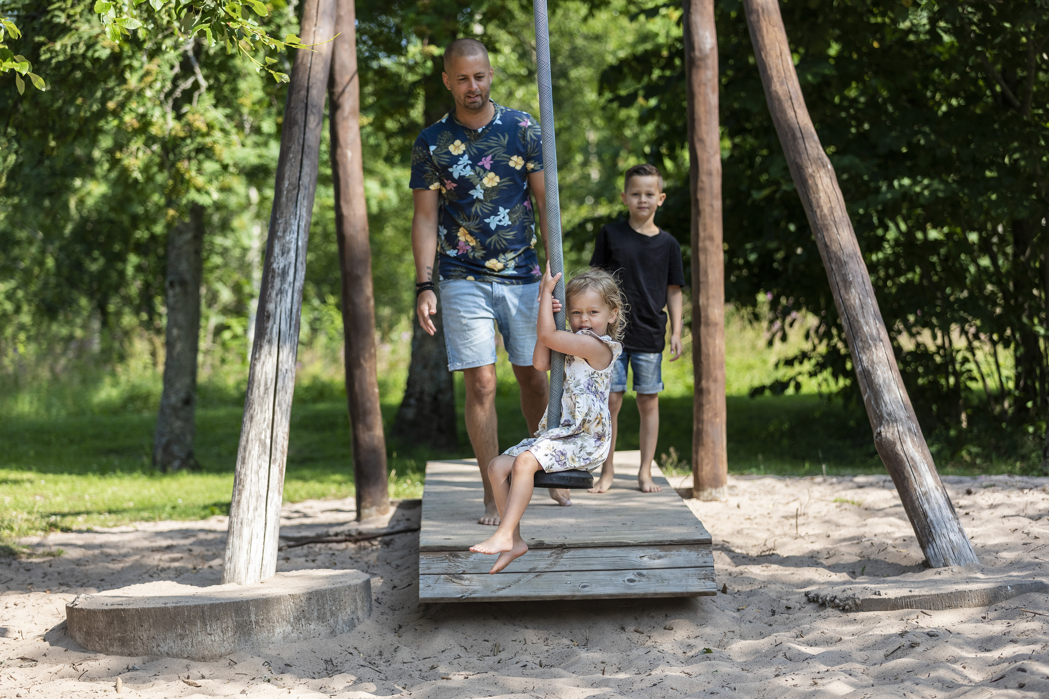 Flicka om åker på en linbana, en man och en pojk står och ser på.