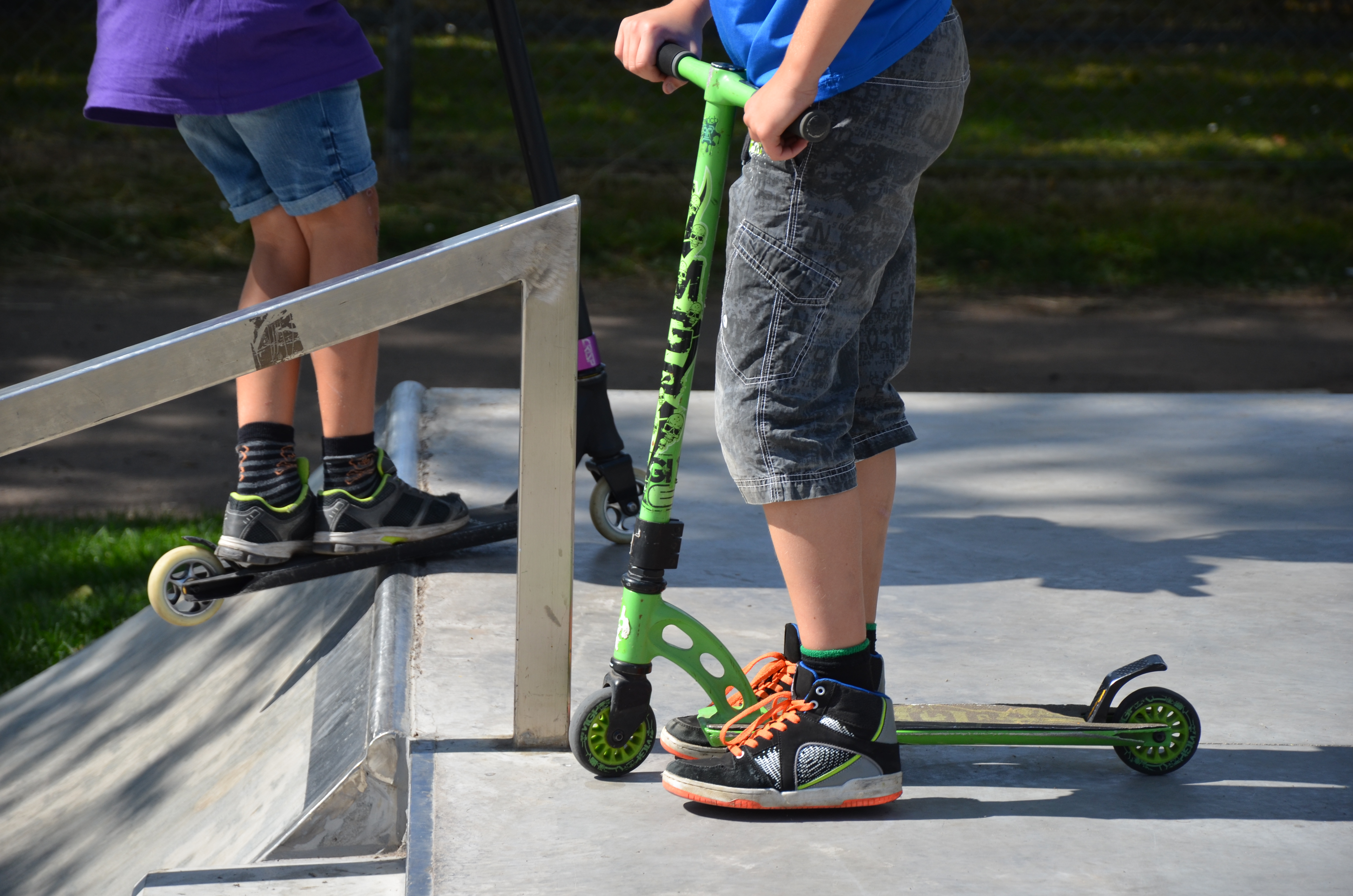 Två killar som står på sparkcyklar.