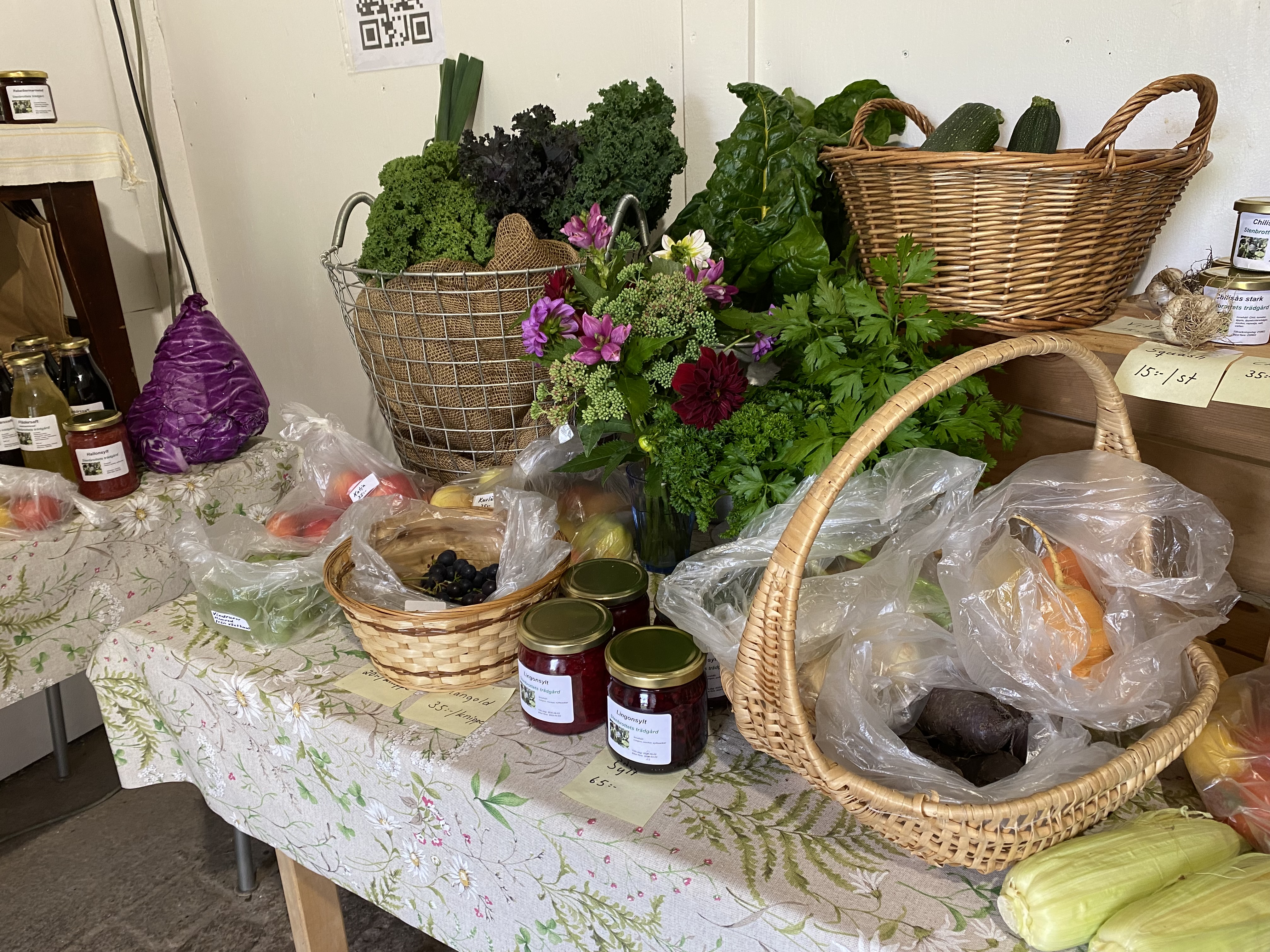 Korgar med grönsaker och syltburkar står på ett bord.