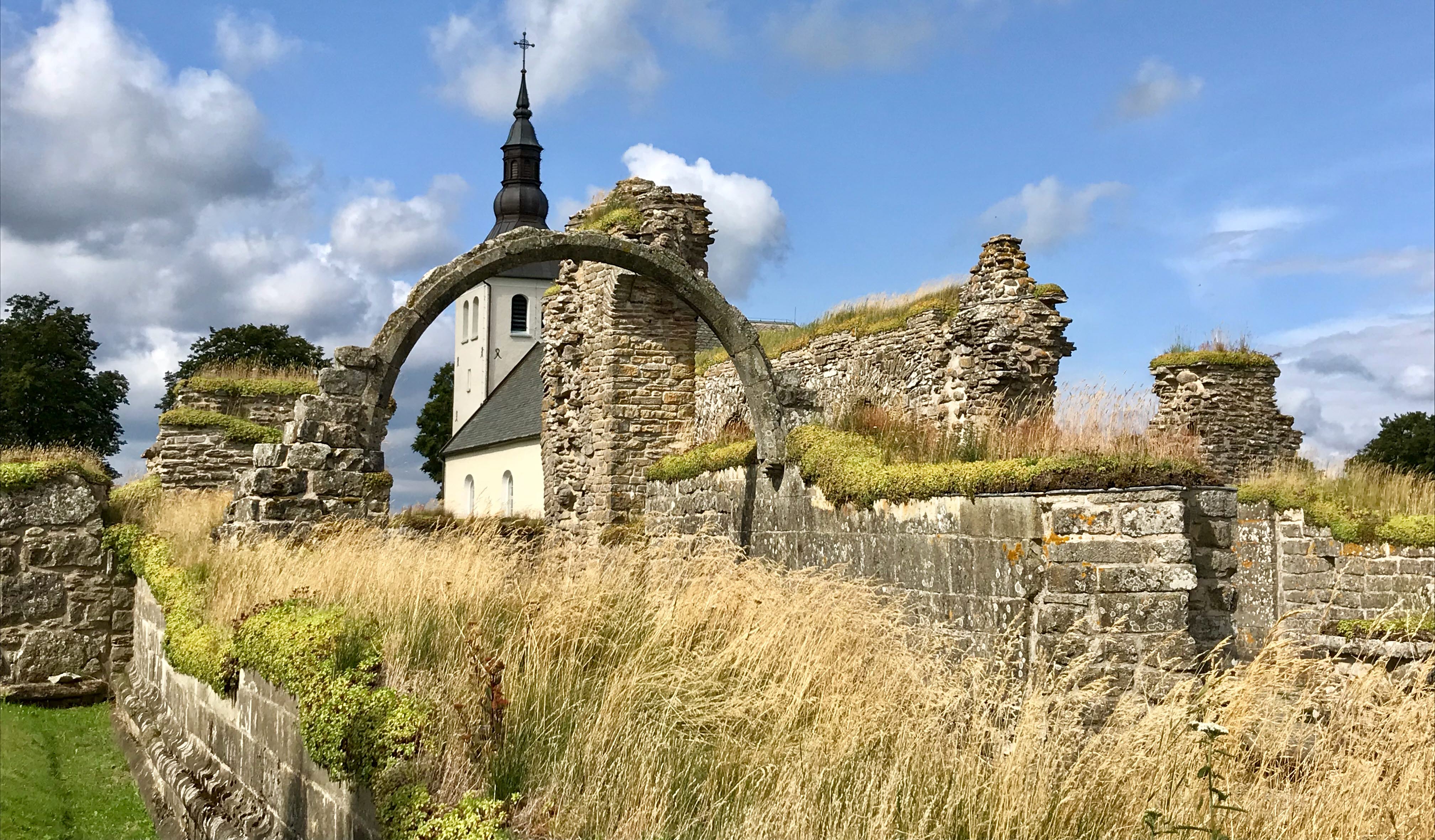 Gudhems klosterruin med Gudhems kyrka i bakgrunden.