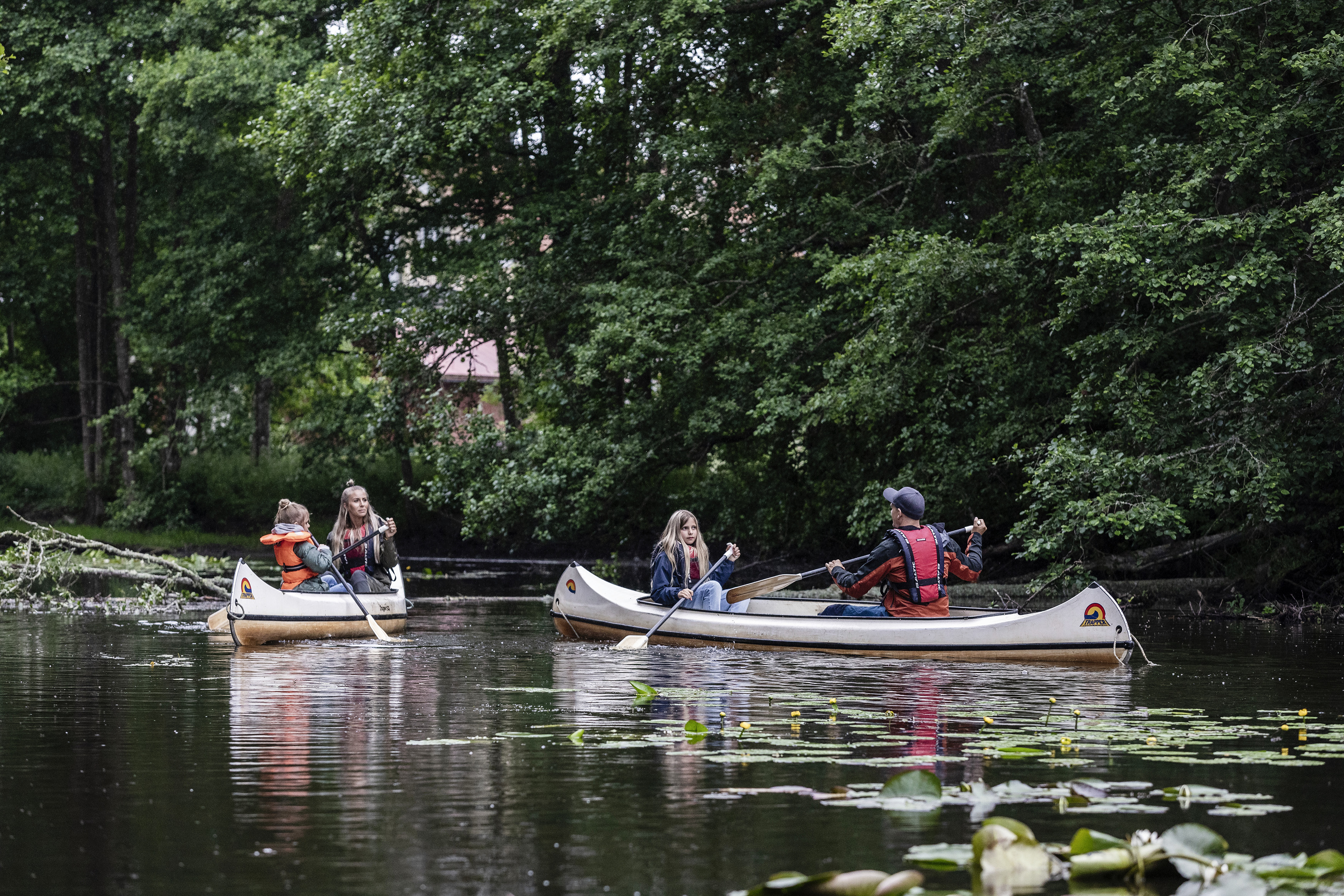 Två kanoter med en kvinna och barn i den ena och en man och barn i den andra.