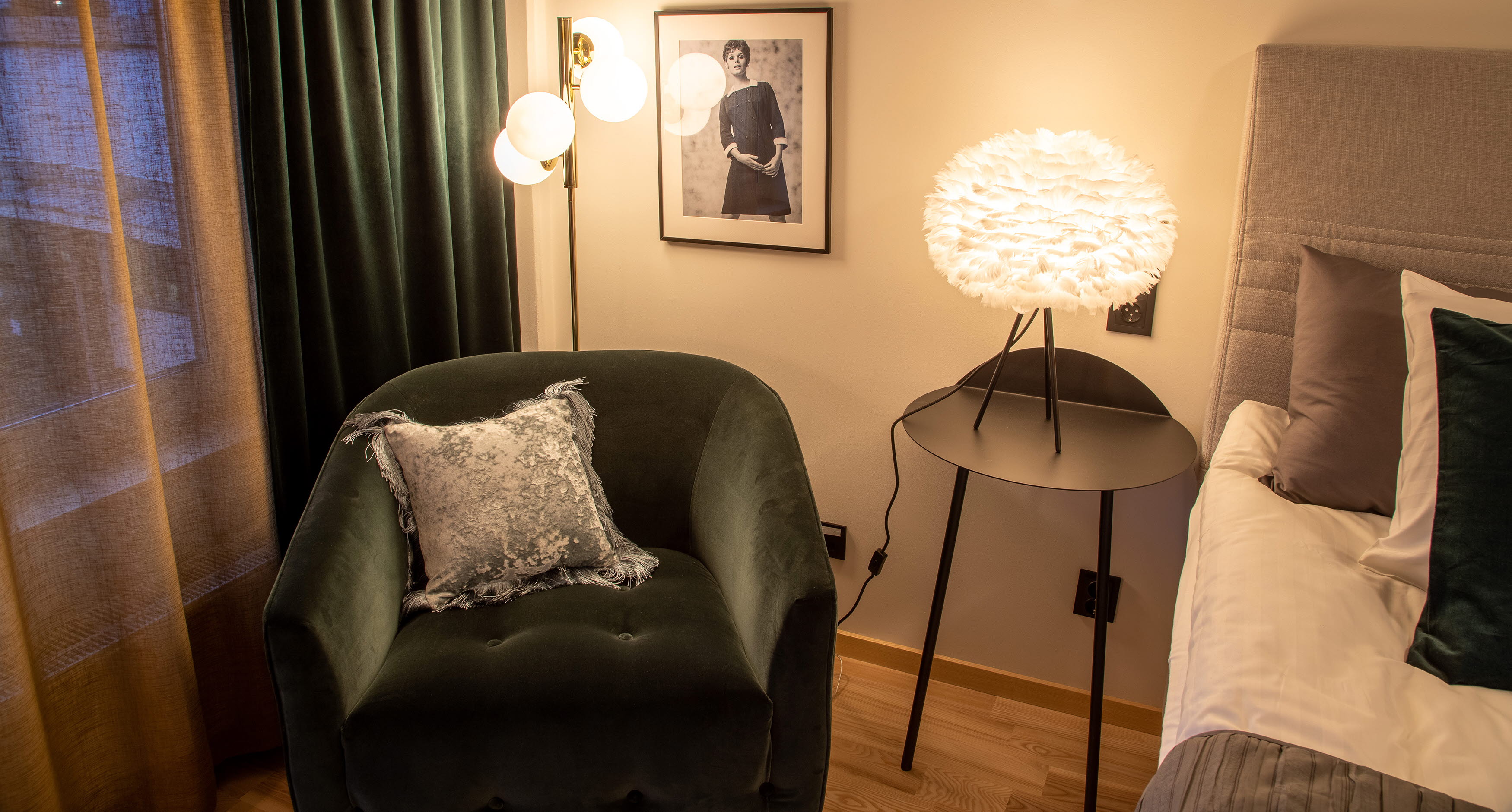 Grön fåtölj med ett svart bord och fjäderlampa.