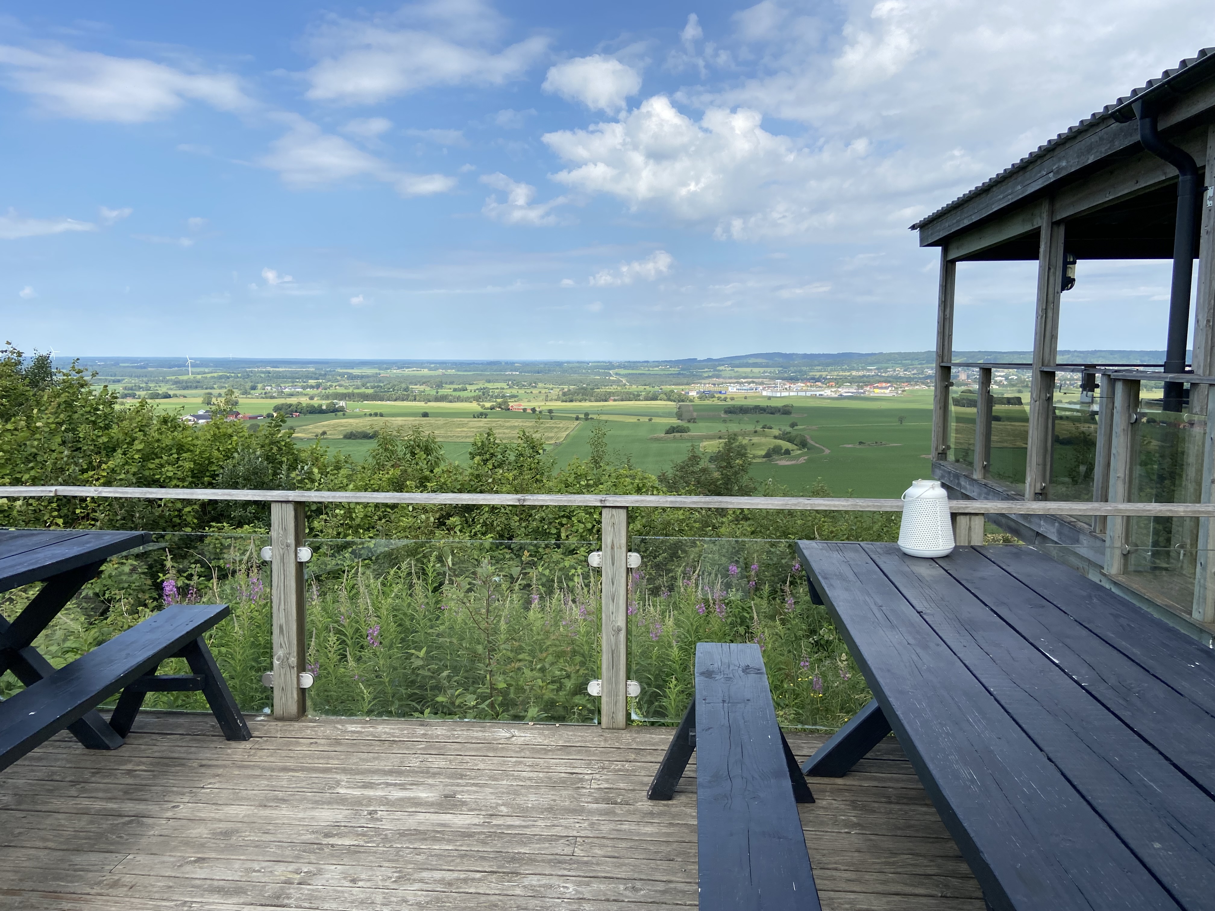 Två svarta bord, en byggnad i kanten på bilden och en vacker utsikt över landskapet.