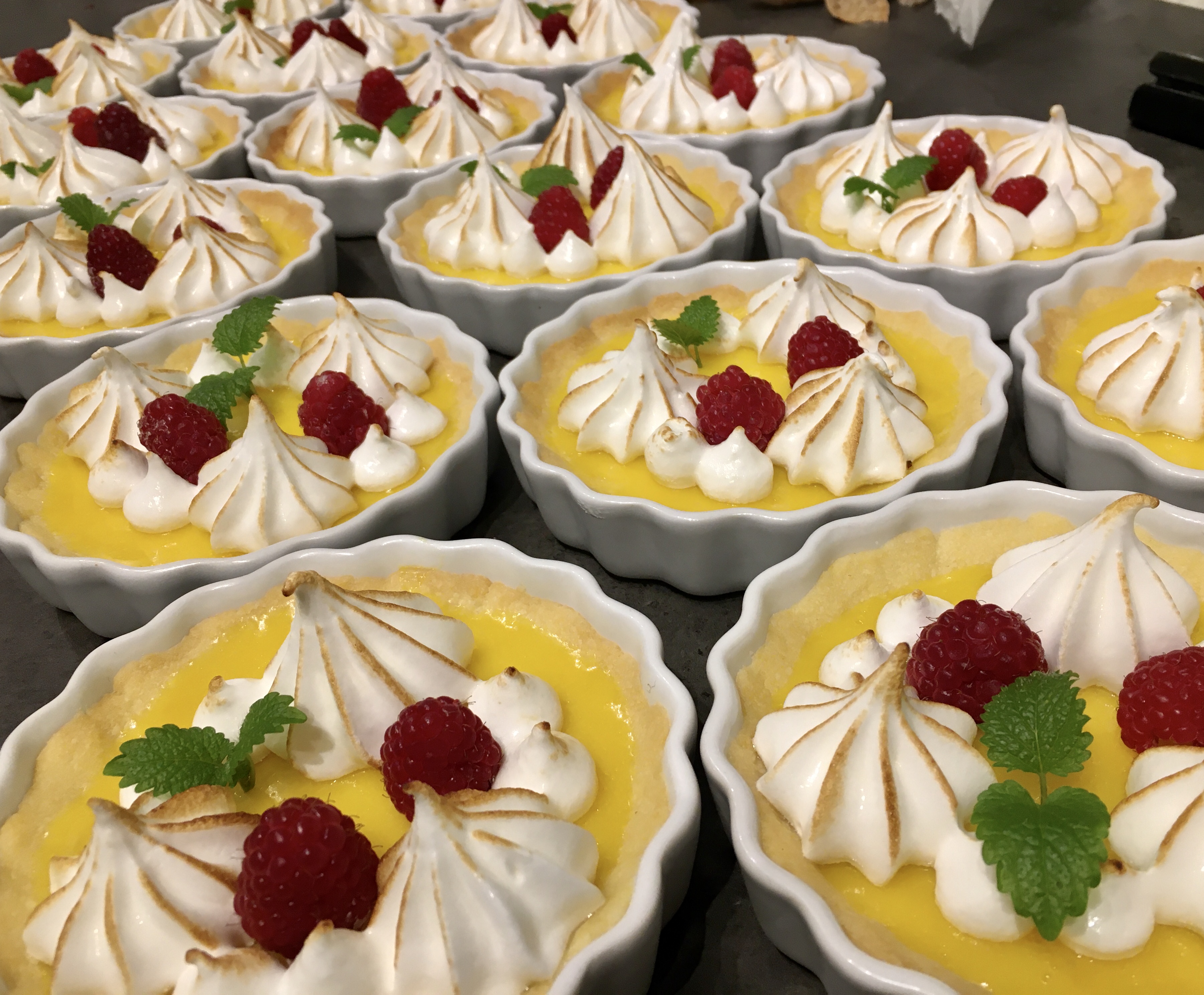 Många små pajer på rad med maräng och hallon.