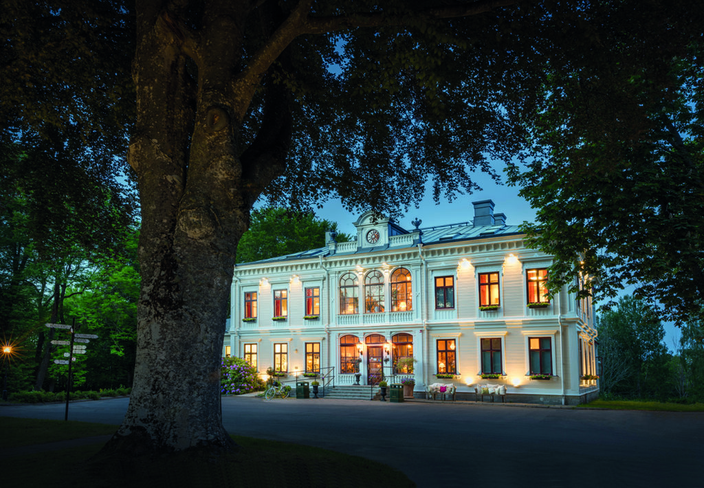 Stort vitt hus med ett träd framför.