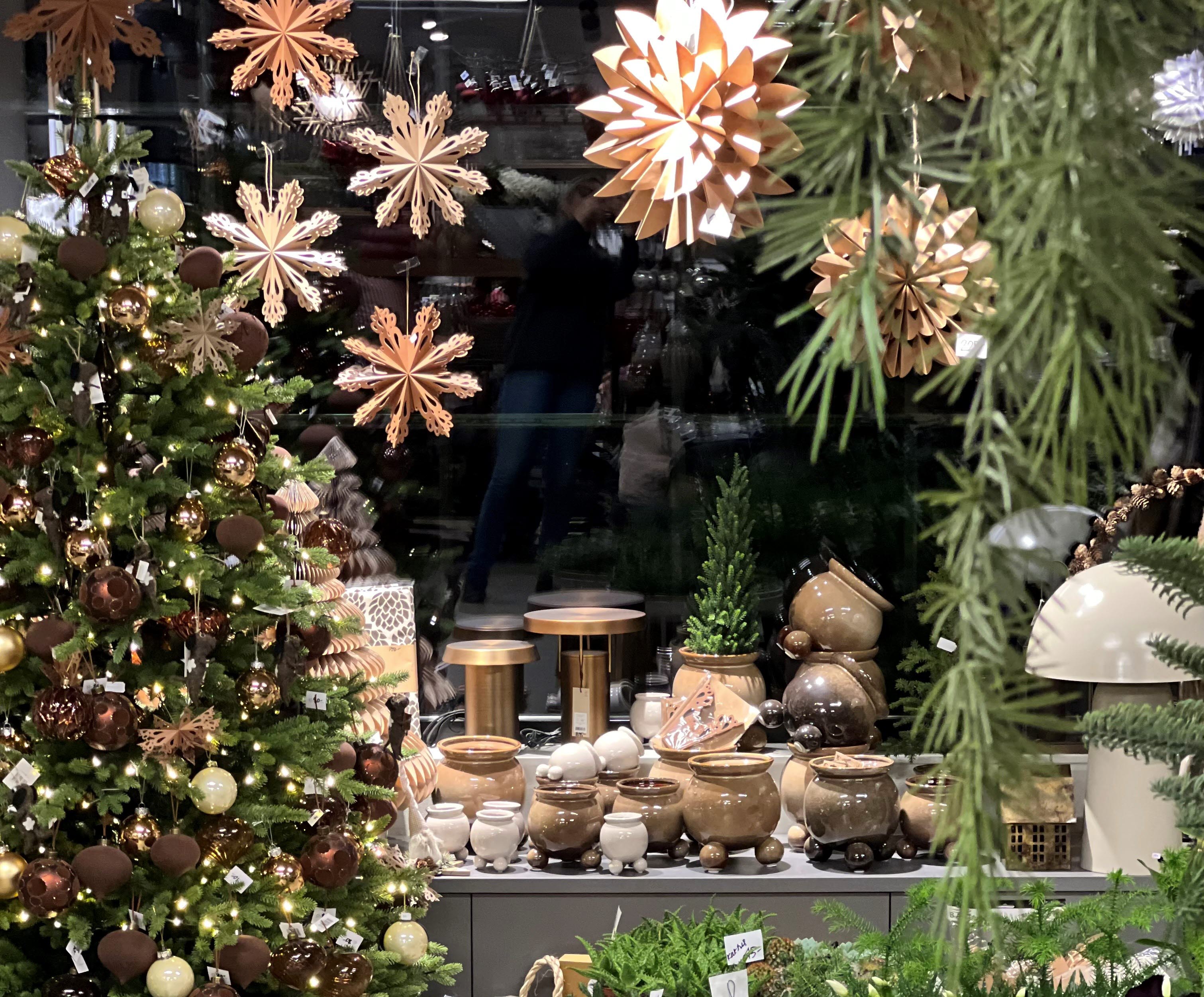 Storefront window with candlesticks in brown cardboard. a Christmas tree with decorations in brown and gold.