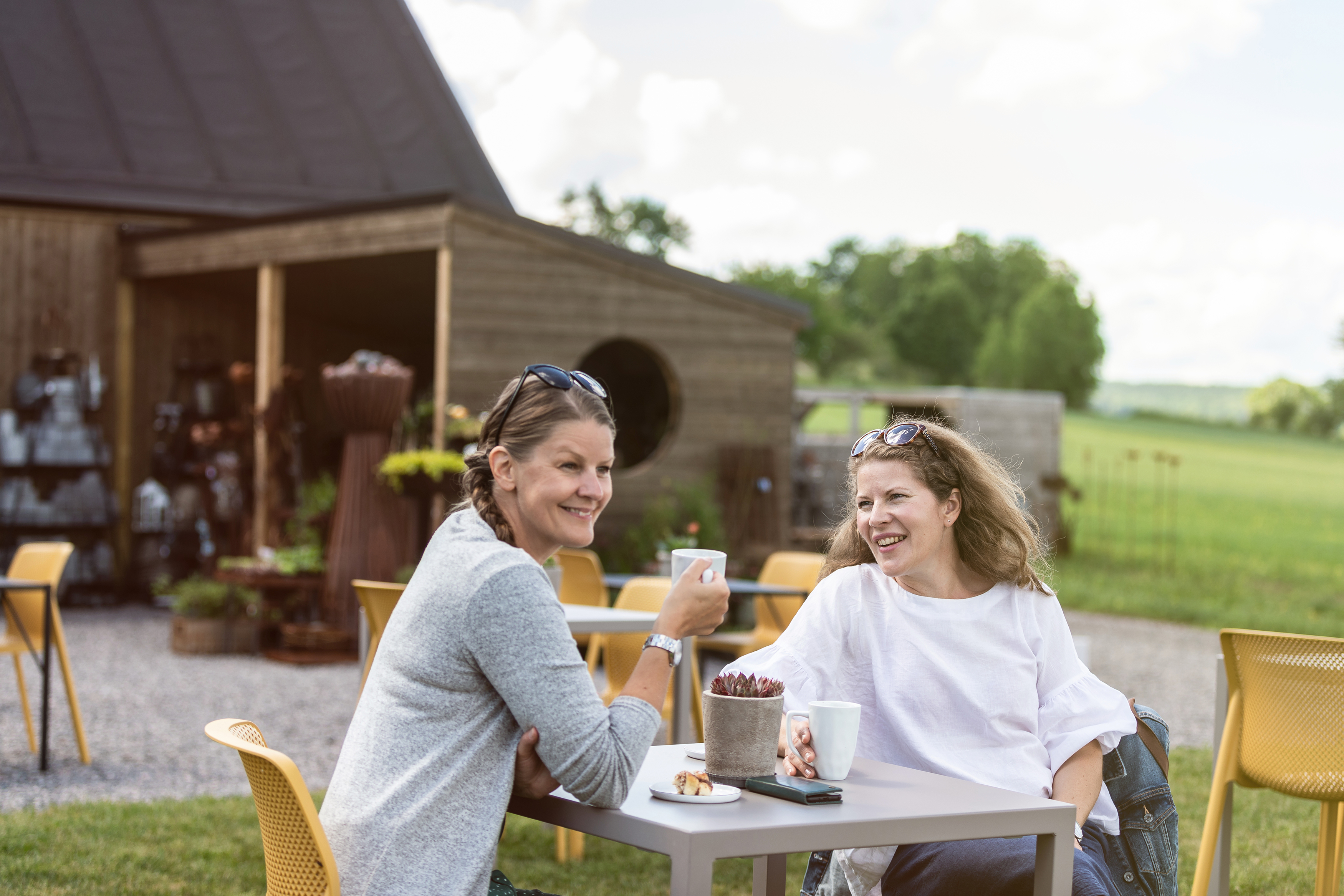 Två kvinnor som sitter och fikar på uteserveringen.
