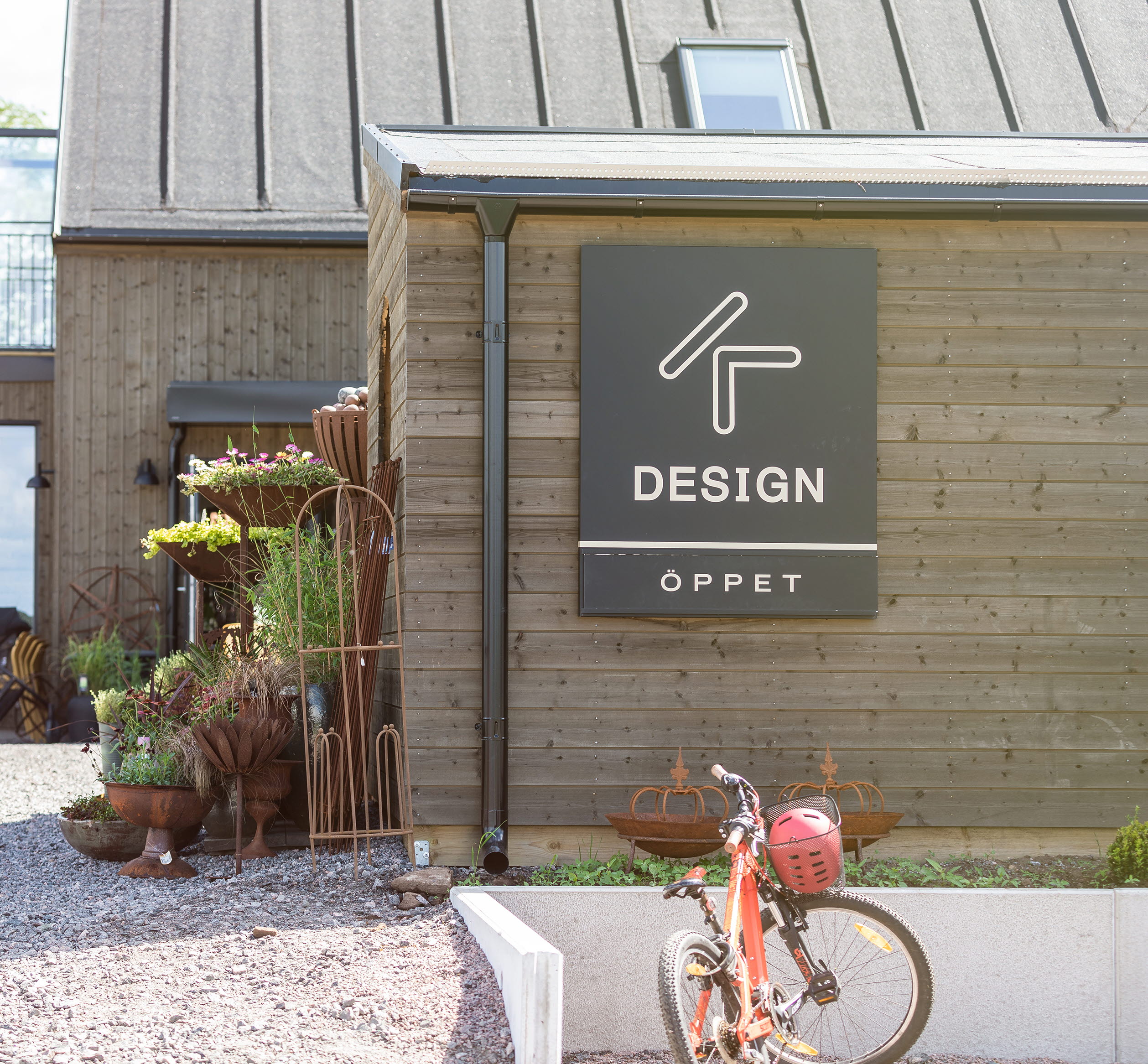 Exteriörbild med en stor skylt med texten Kdesign. Caféets uteservering syns i bakgrunden.