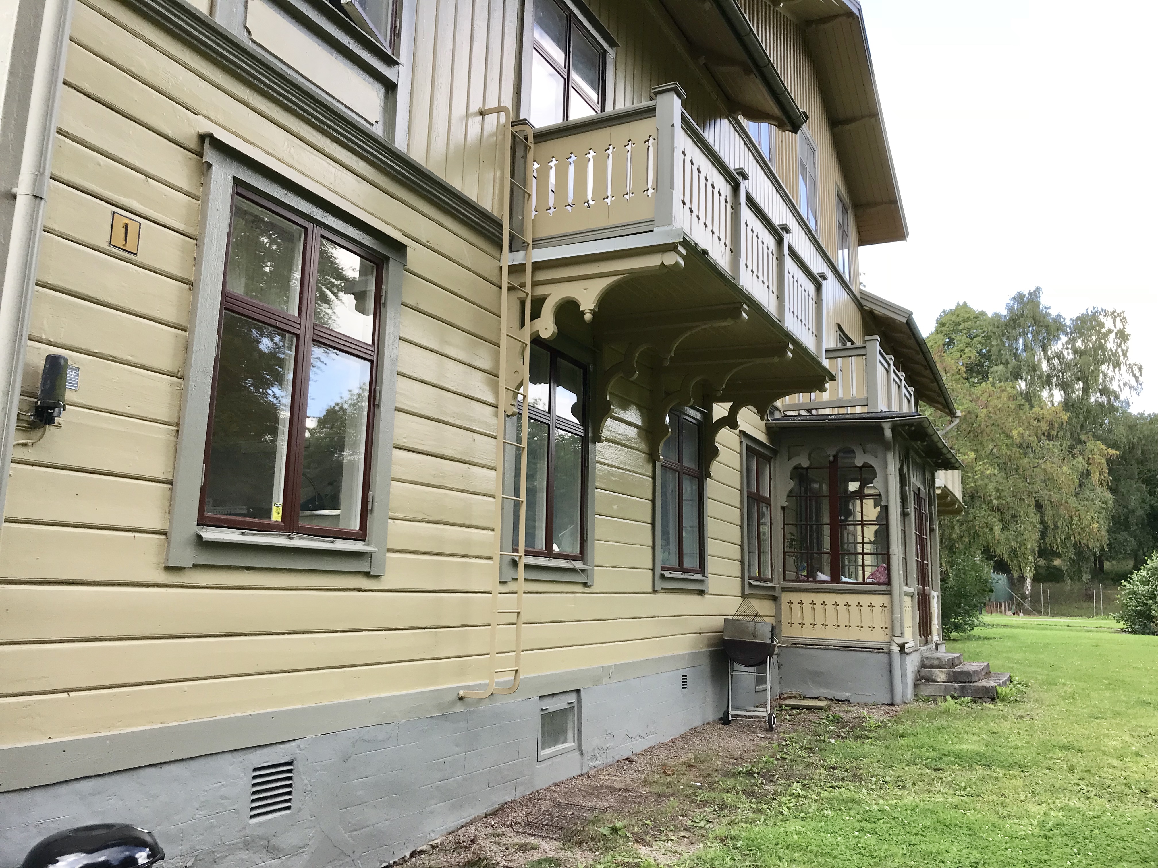 Gul stor träbyggnad med veranda.