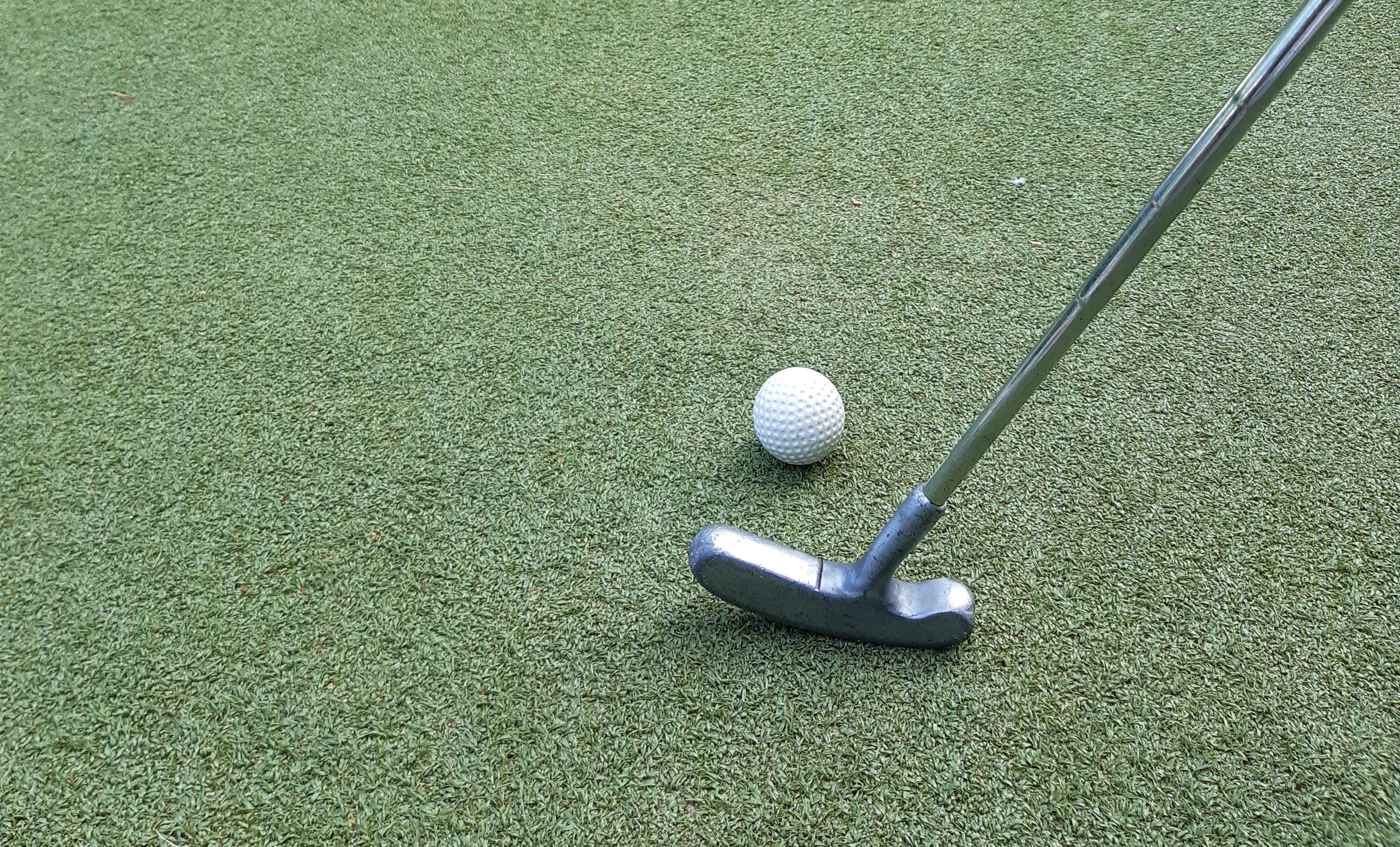 Golfklubba och boll som ska skjuta mot ett hål.