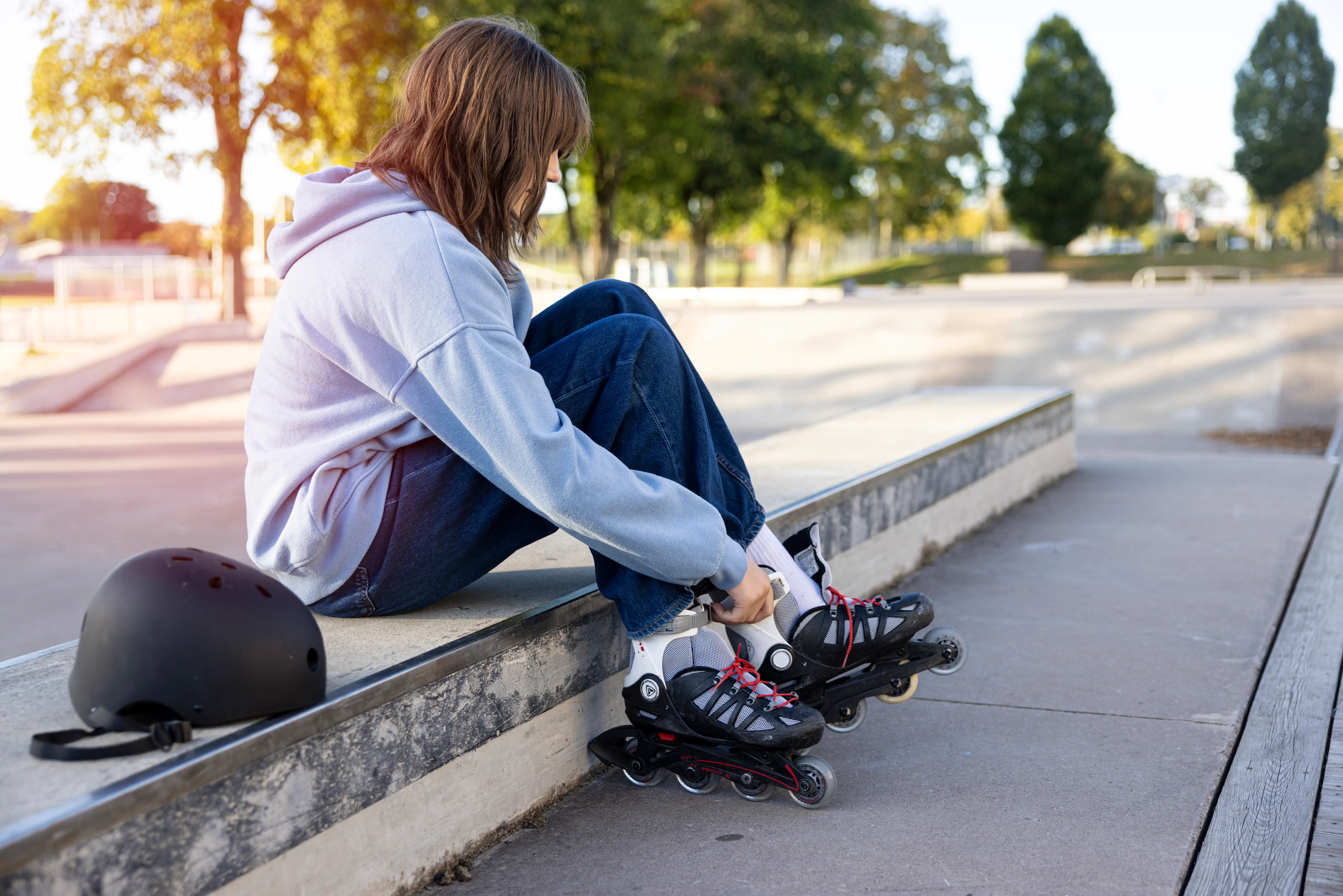 En ungdom sitter i en betongtrappa och tar på sig ett par inlines