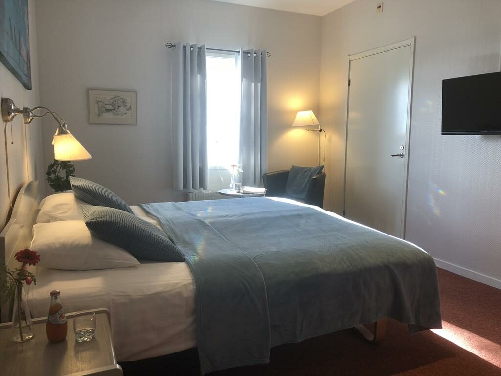 Bright room with a double bed that has a gray / blue bedspread.