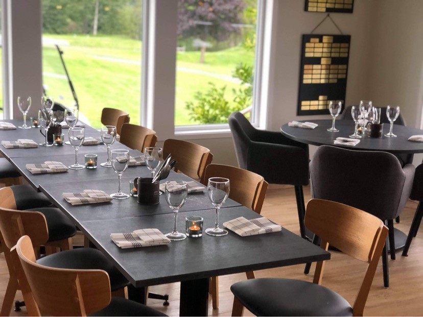 Svarta bord och stolar i träfärg. Dukning med glas, bestick och servetter.