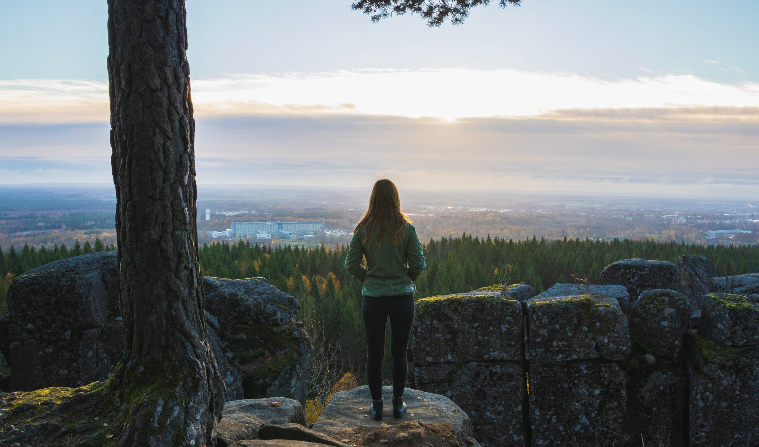Kvinna som står med ryggen mot kameran och kikar ut över en vacker utsikt.