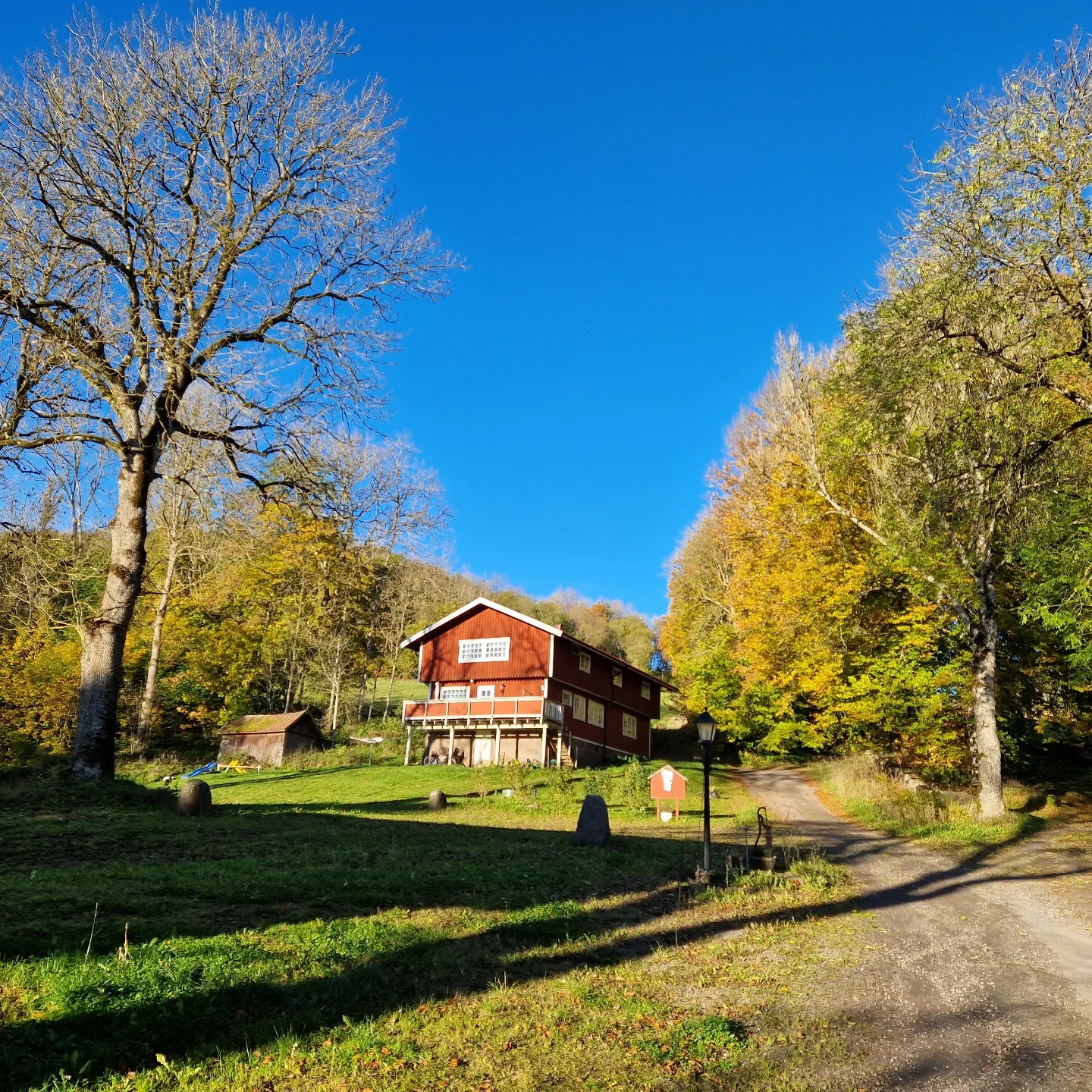 Rött hus på landet med en grusväg fram till byggnaden.