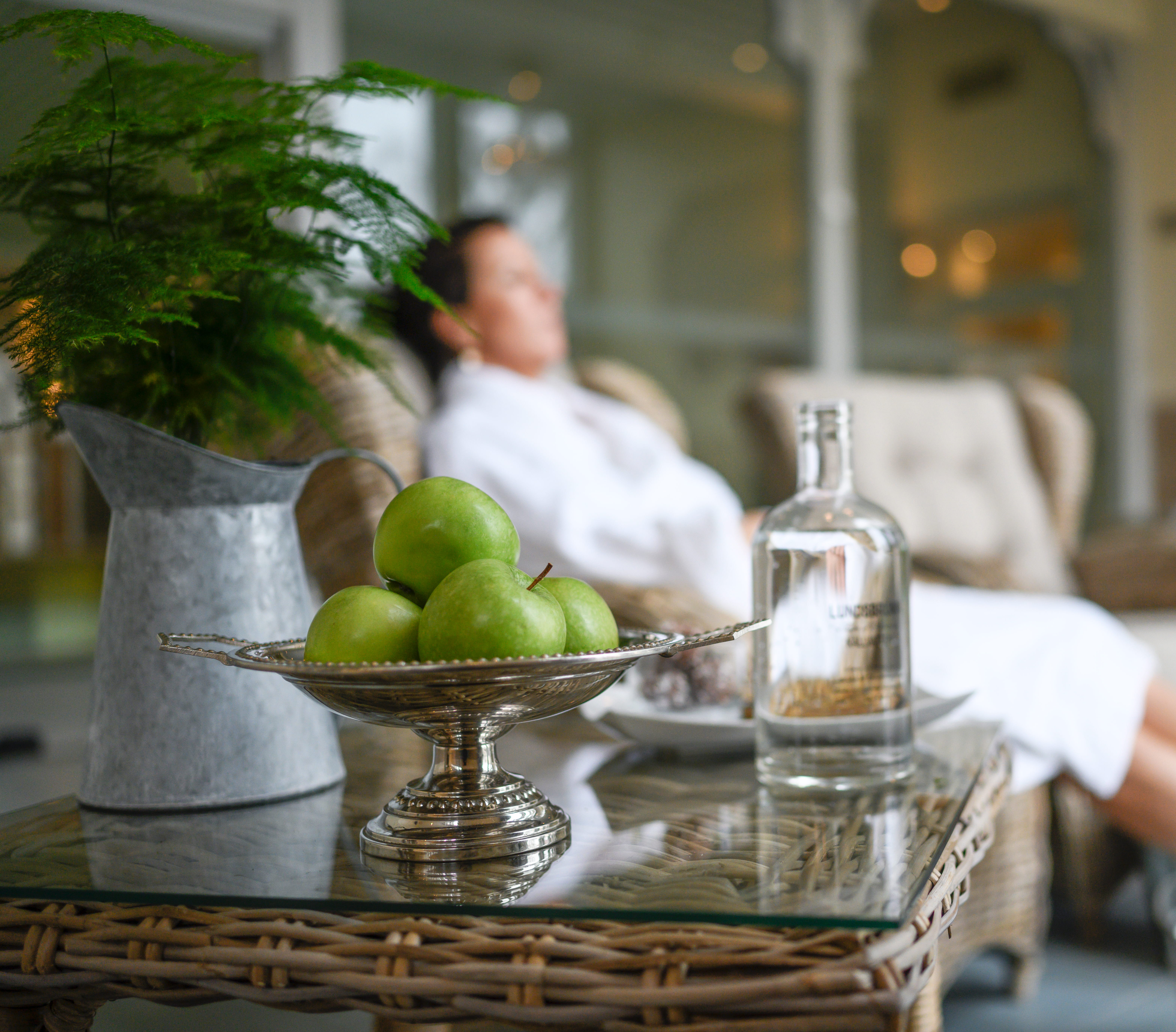 Man som sitter i morgonrock och vilar sig. Äpplen ligger i en skål.