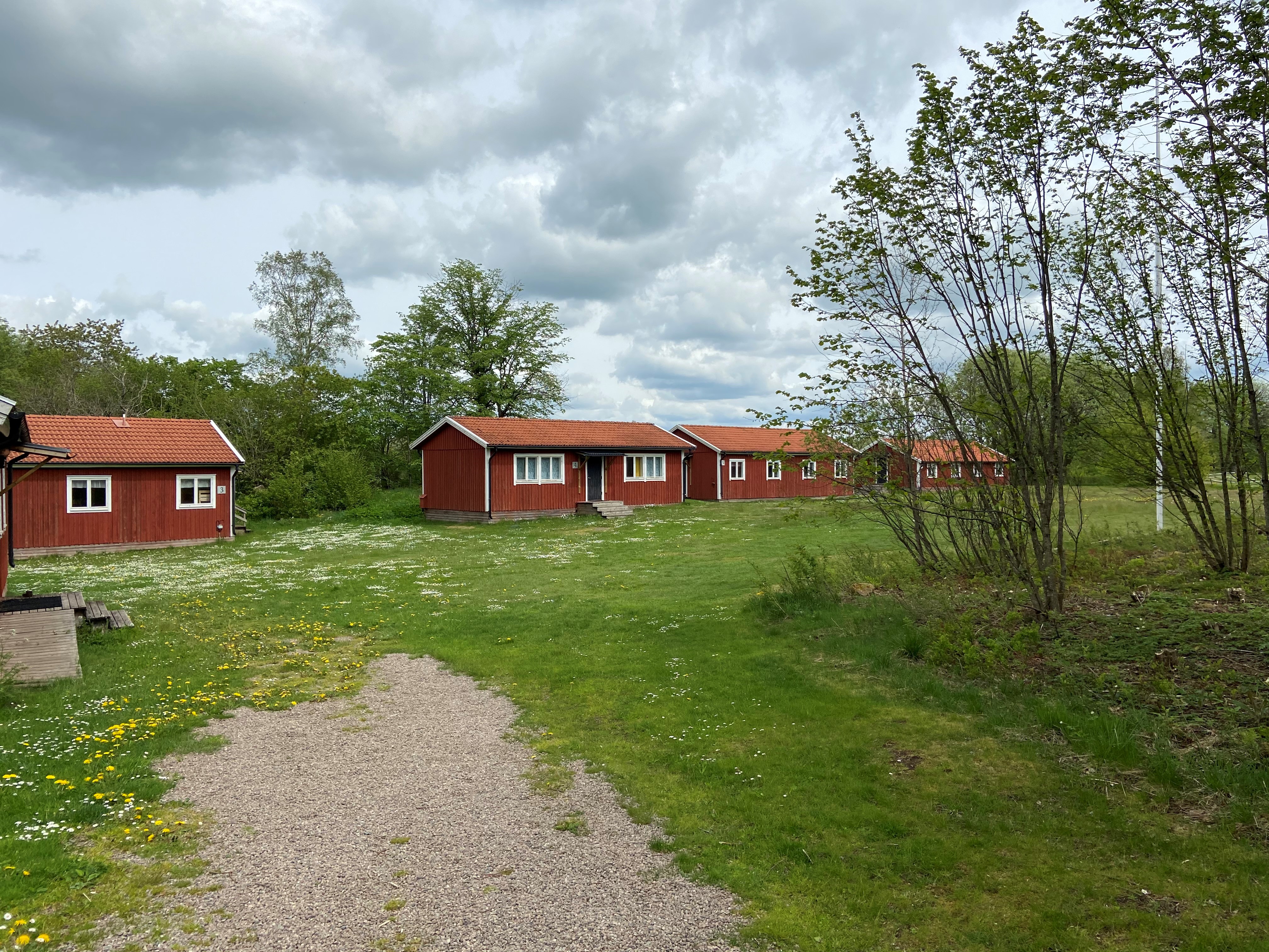 4 röda stugor i rad, stor gräsplan framför.