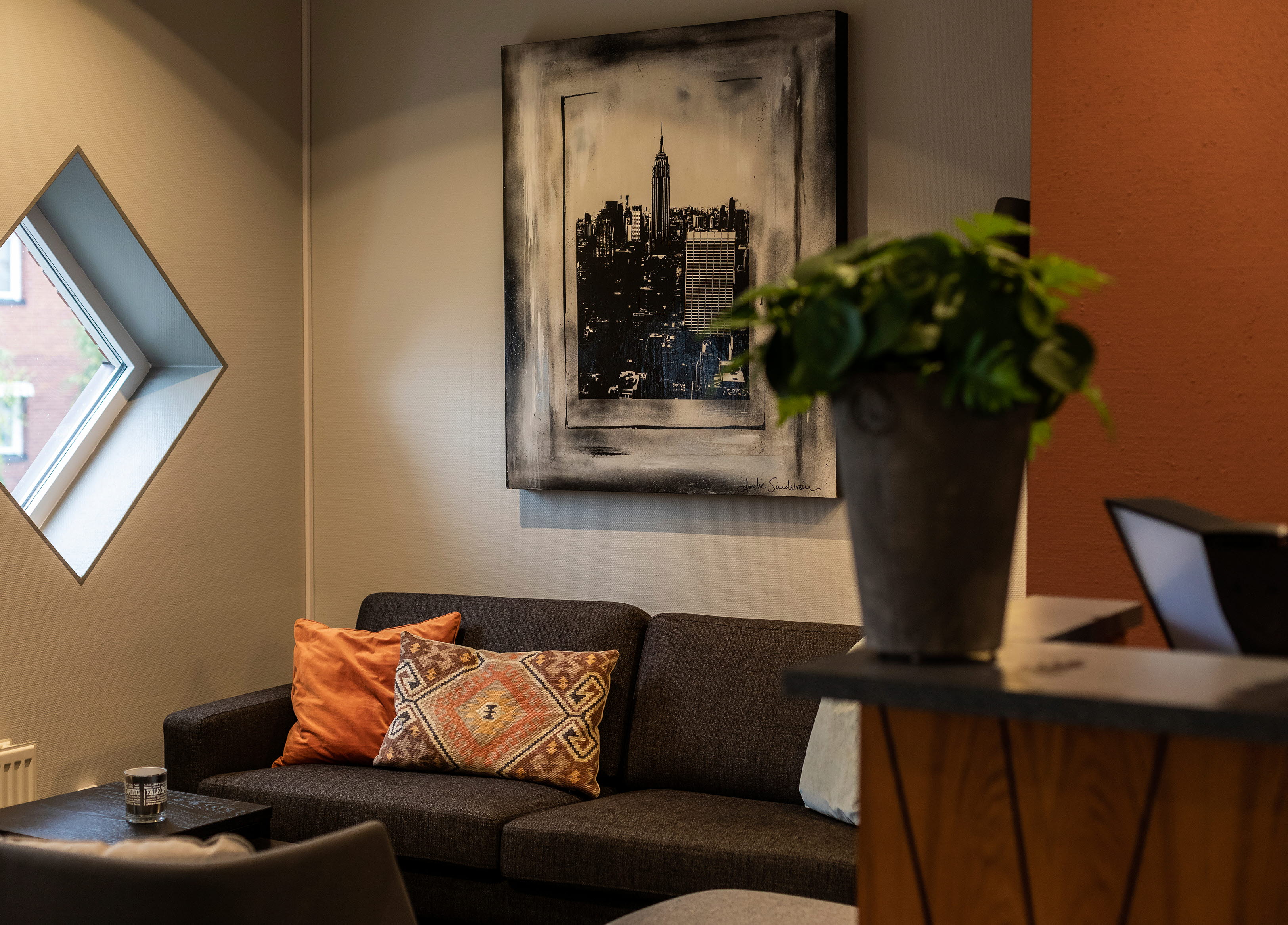 Hotellreception med gråa soffor, orange vägg bakom. 