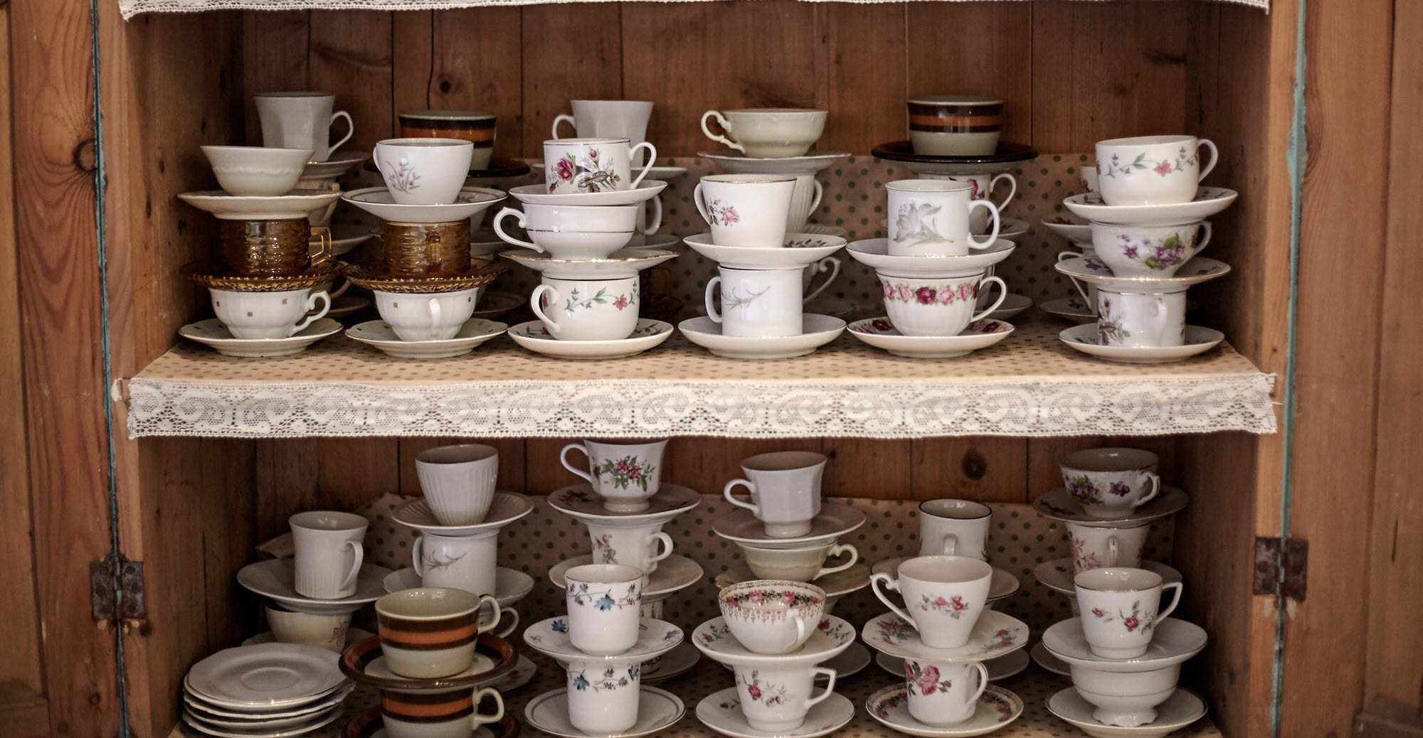 Fullt med kaffekoppar staplade i ett skåp.