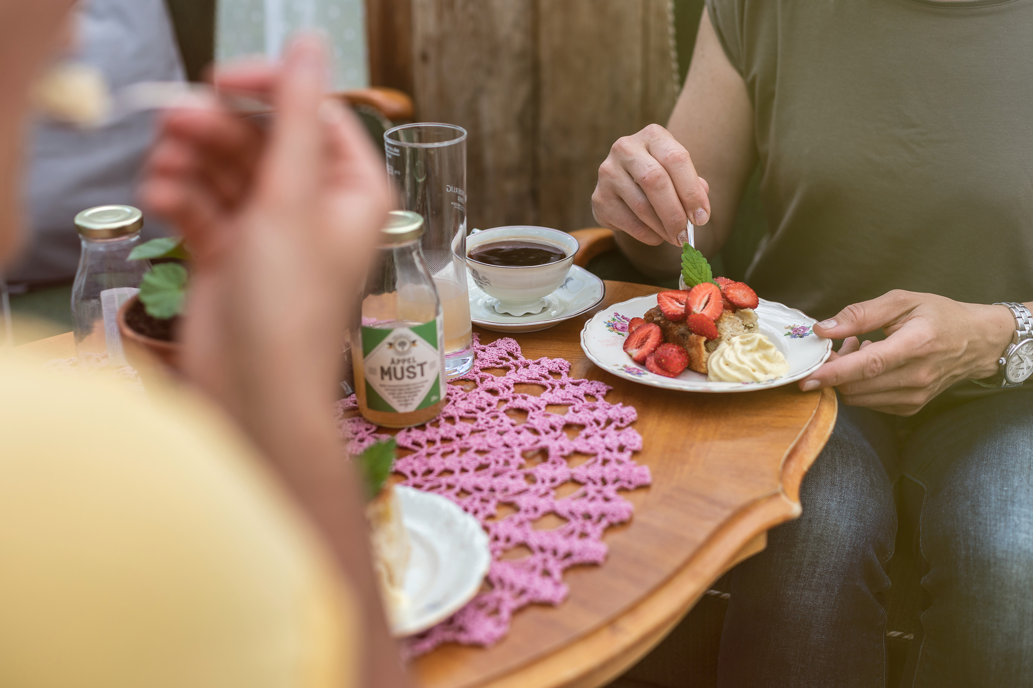 Fikabord med en kaka med jordgubbar och grädde.
