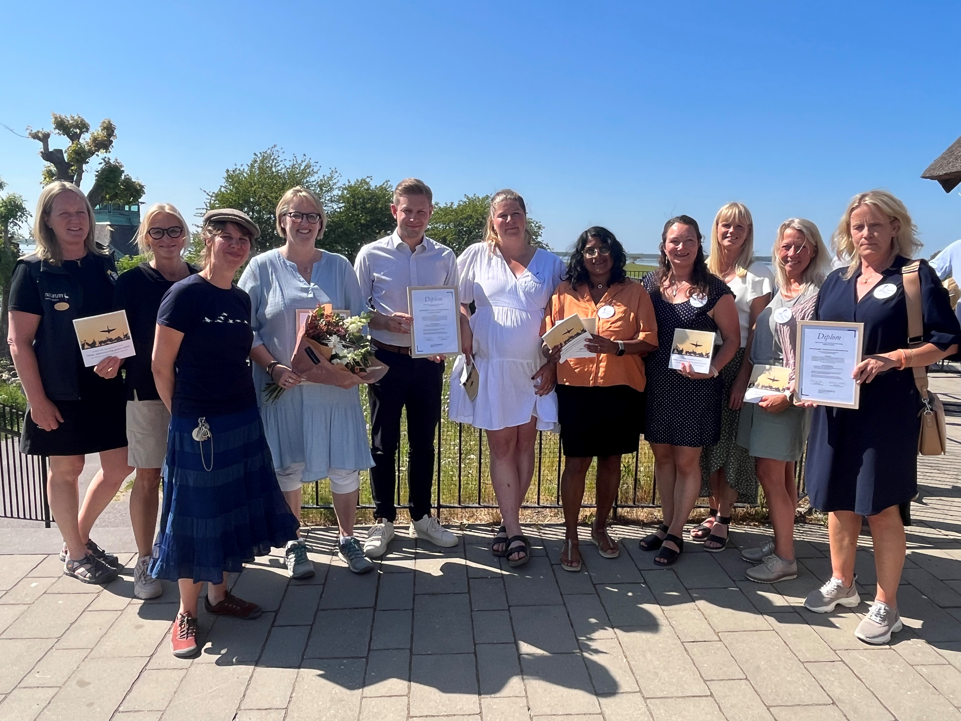 En grupp människor, några av dem håller upp ett diplom.