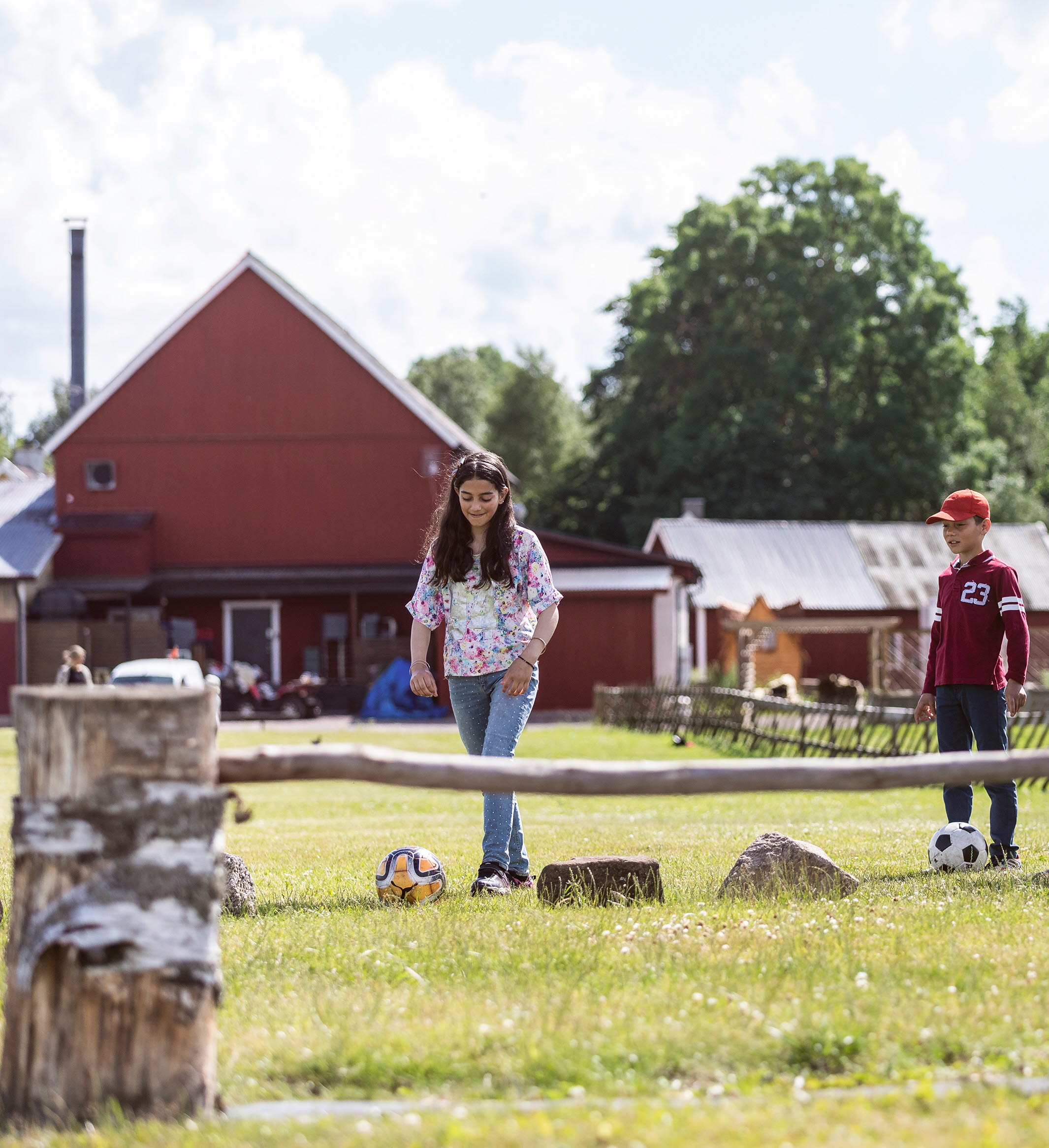 Flicka som sparkar fotboll över ett hinder. Familjen står vid sidan och hejar på.
