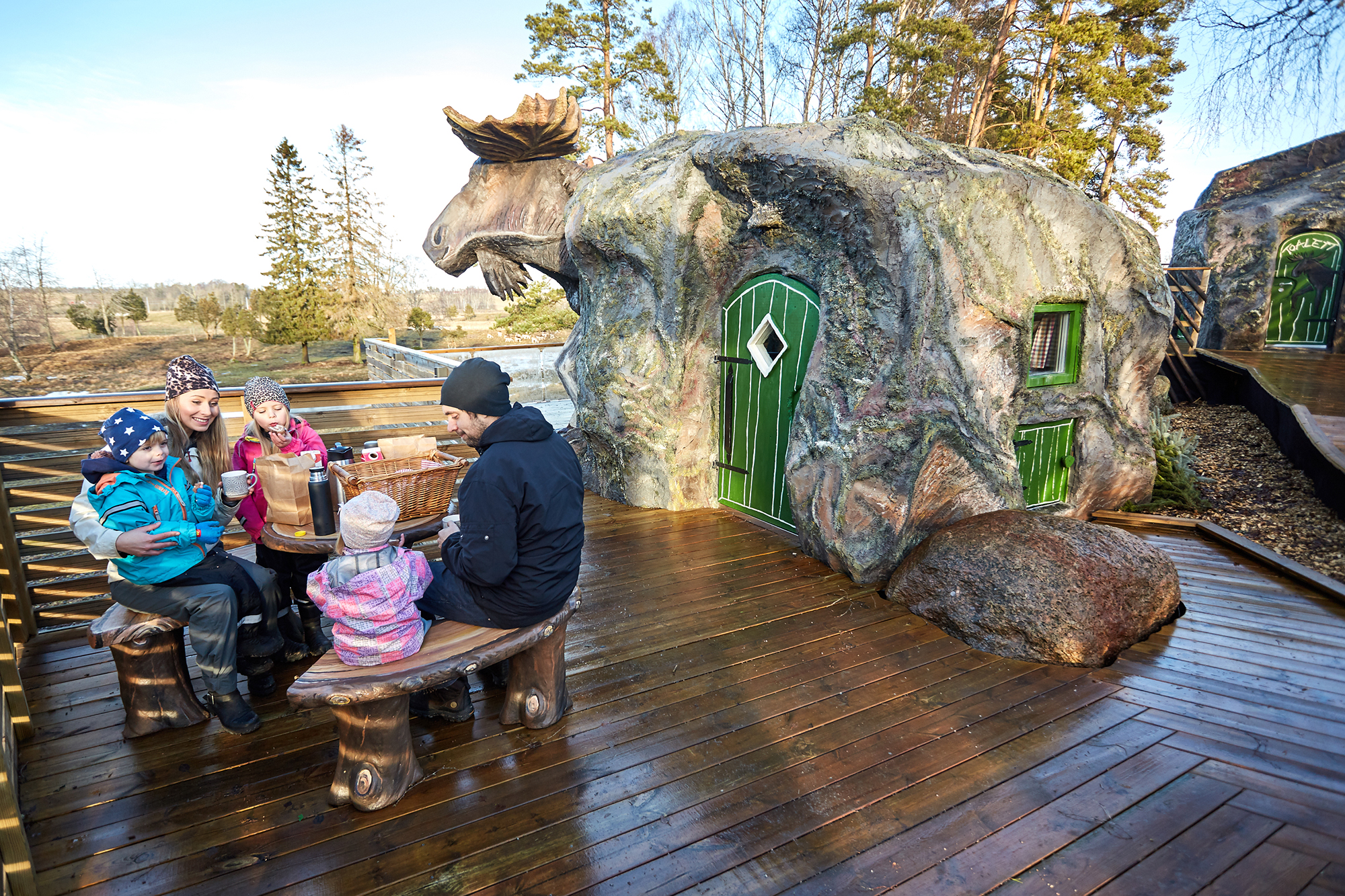 Familj som sitter och äter frukost utanför älgboendet.