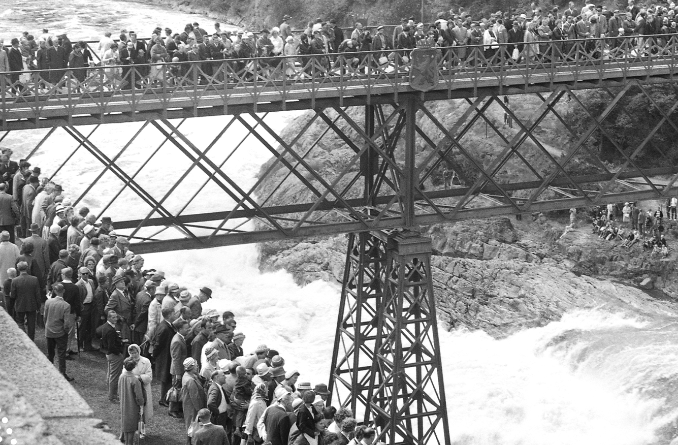Svartvit bild på den gamla Oscarsbron fylld av människor som ser ett fallpåsläpp