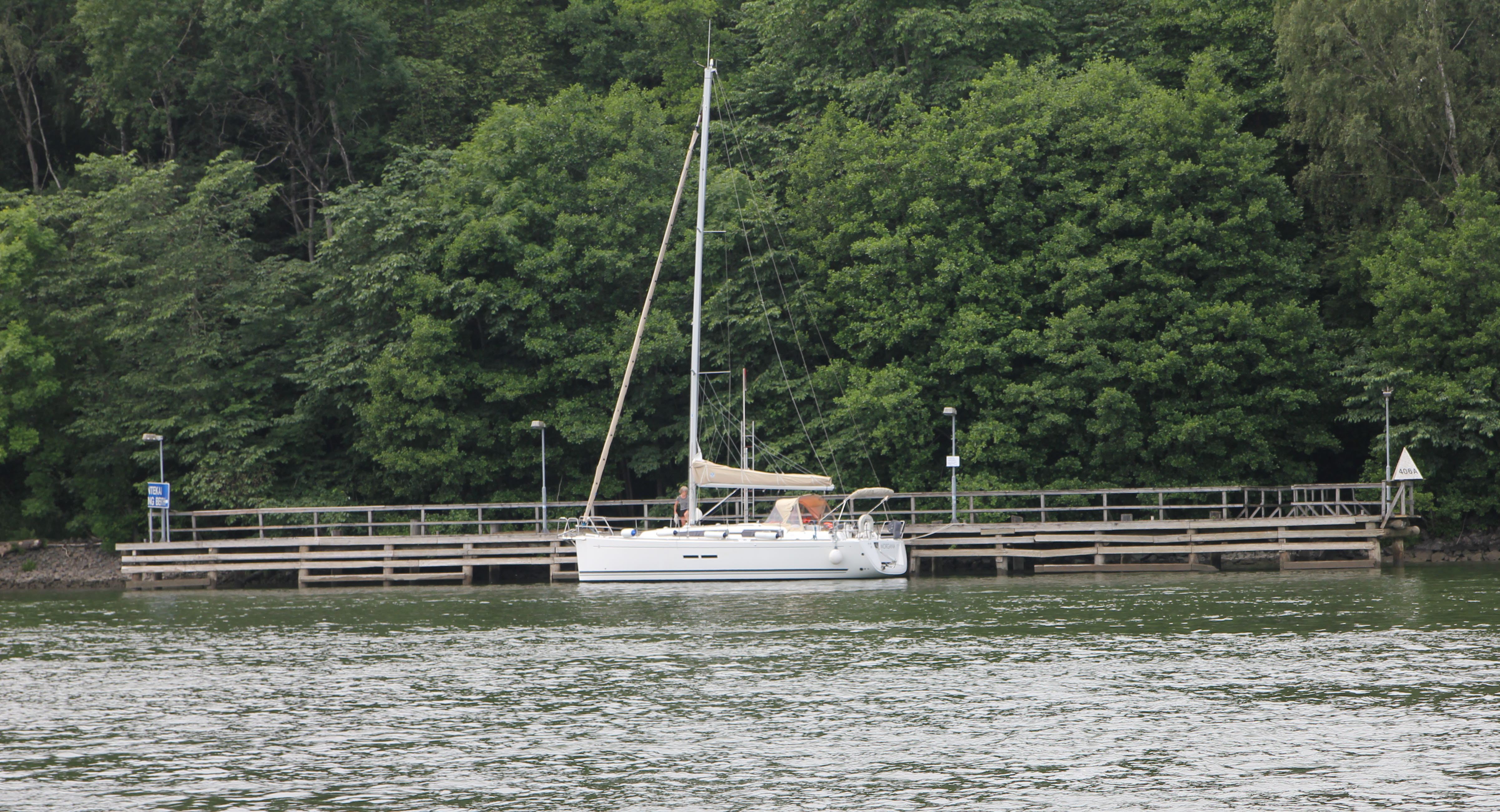 Vit segelbåt vid en väntkaj.