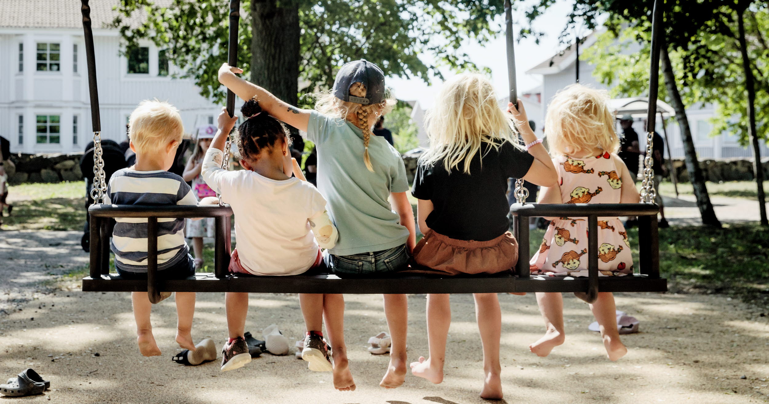 barn gungar på en stor gunga iklädda sommarkläder