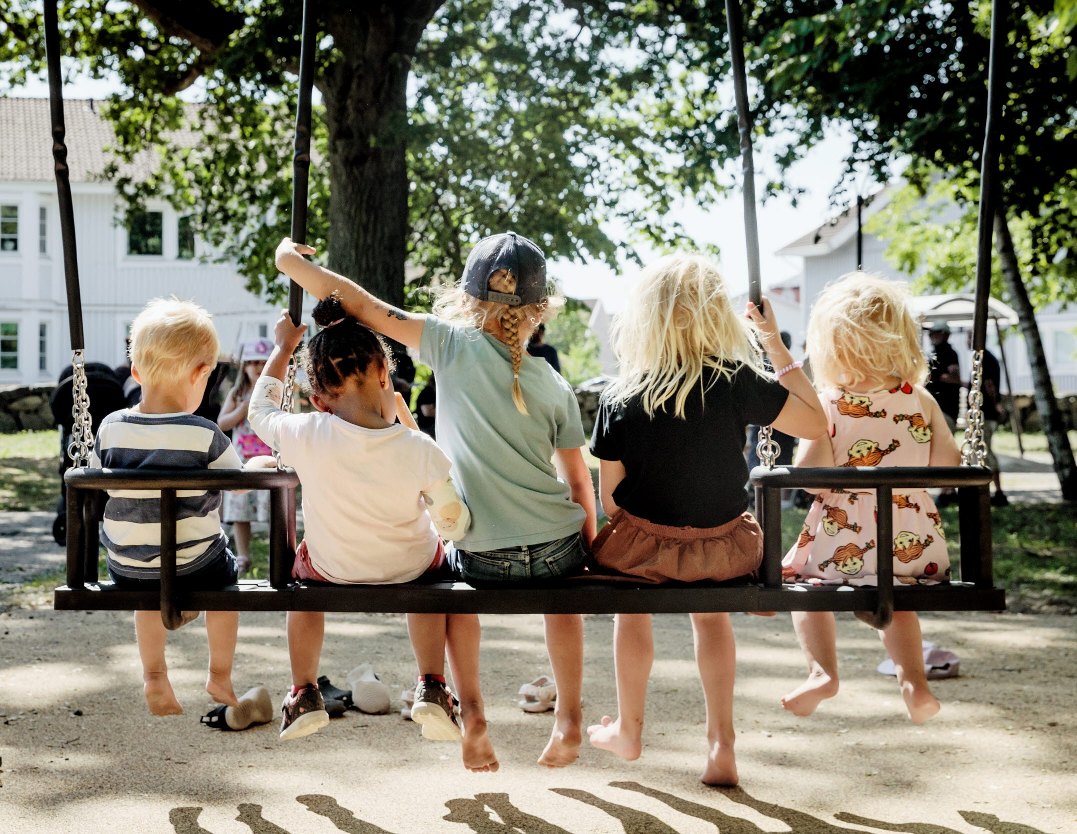 barn gungar på en stor gunga iklädda sommarkläder