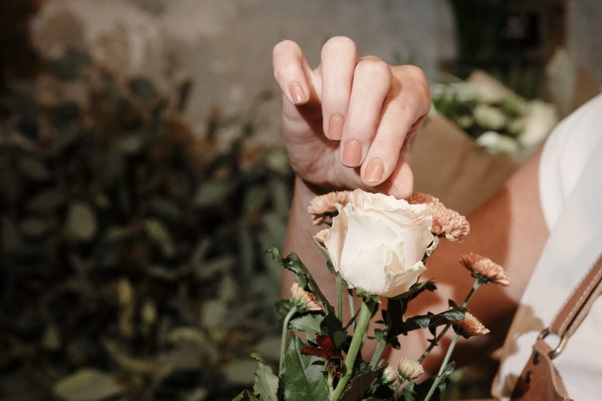 Gröna gåvan florist i Grästorp, hand håller i ros