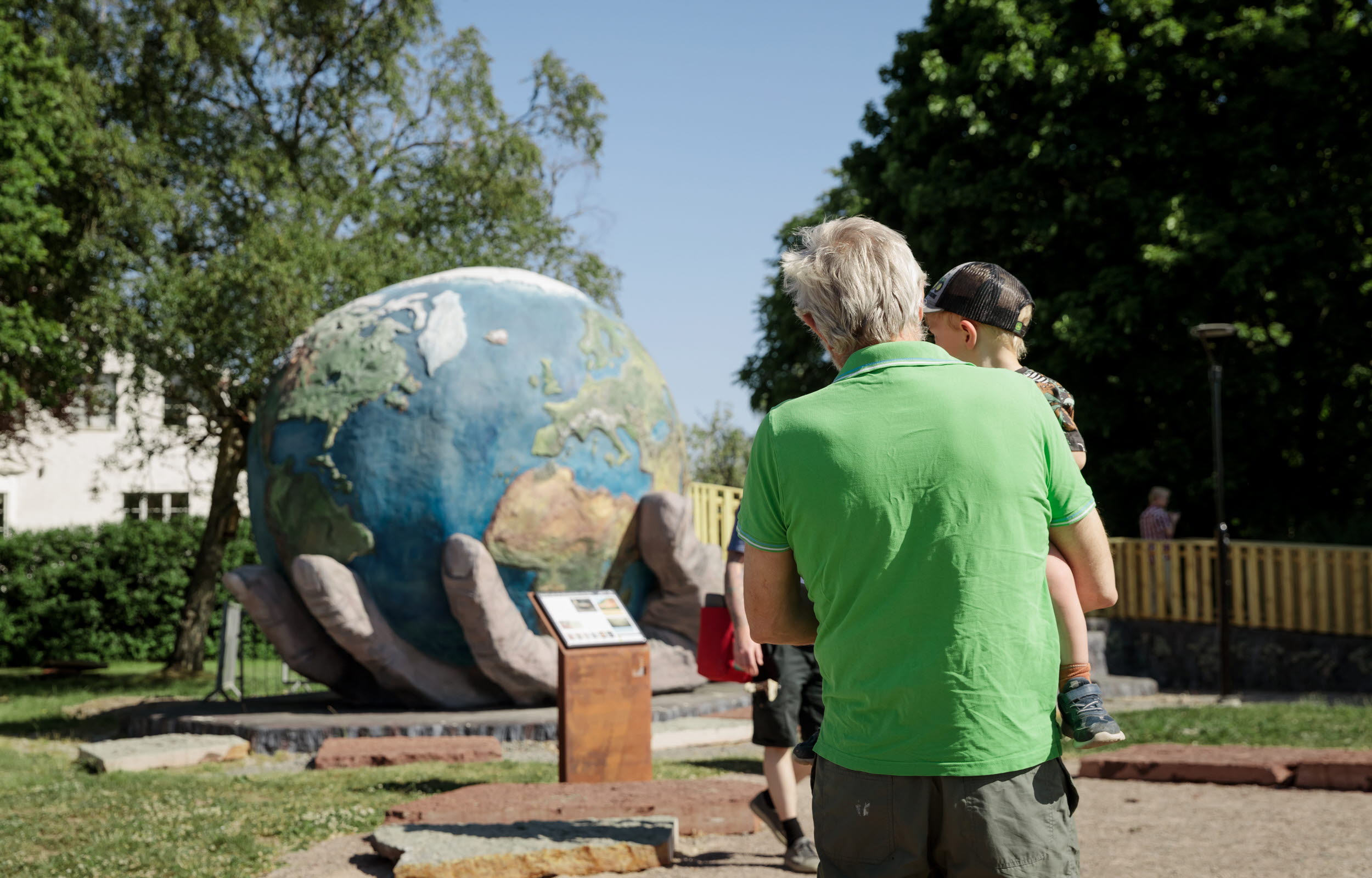 Man och barn tittar på jordgloben på lekparken Lilla Bergaparken i Grästorps kommun
