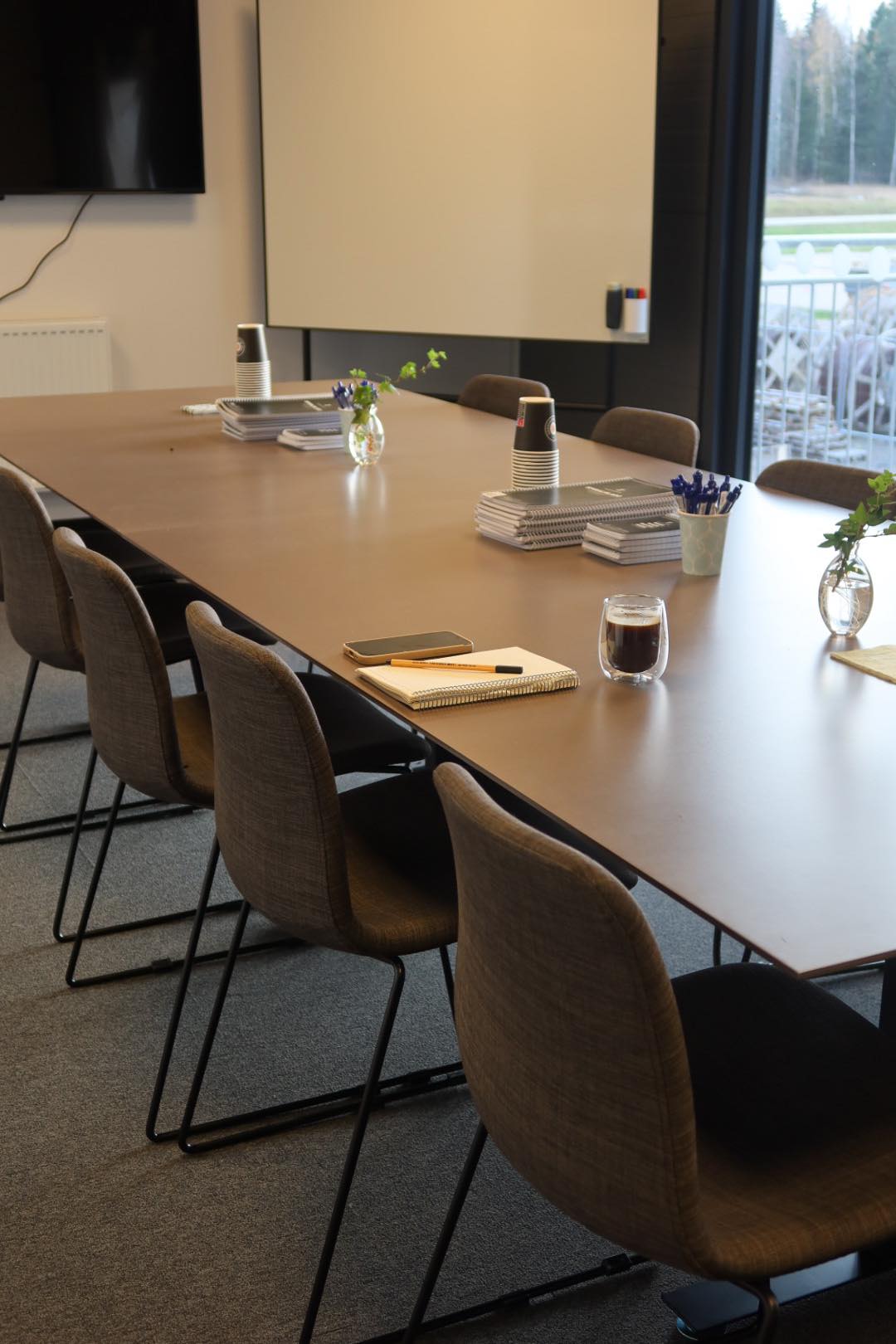 Möteslokal med ett långt bord och stolar. 