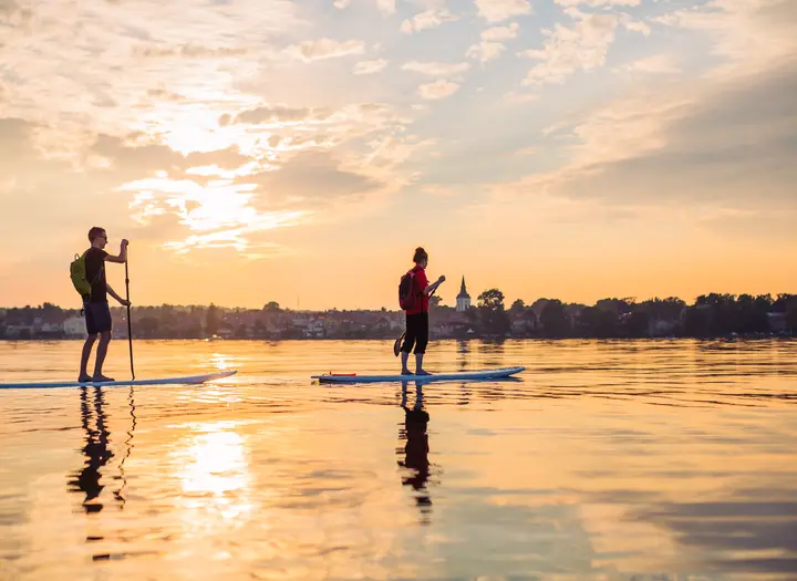 Two people are slowly paddling on a Stand up paddleboard on lake Vättern.