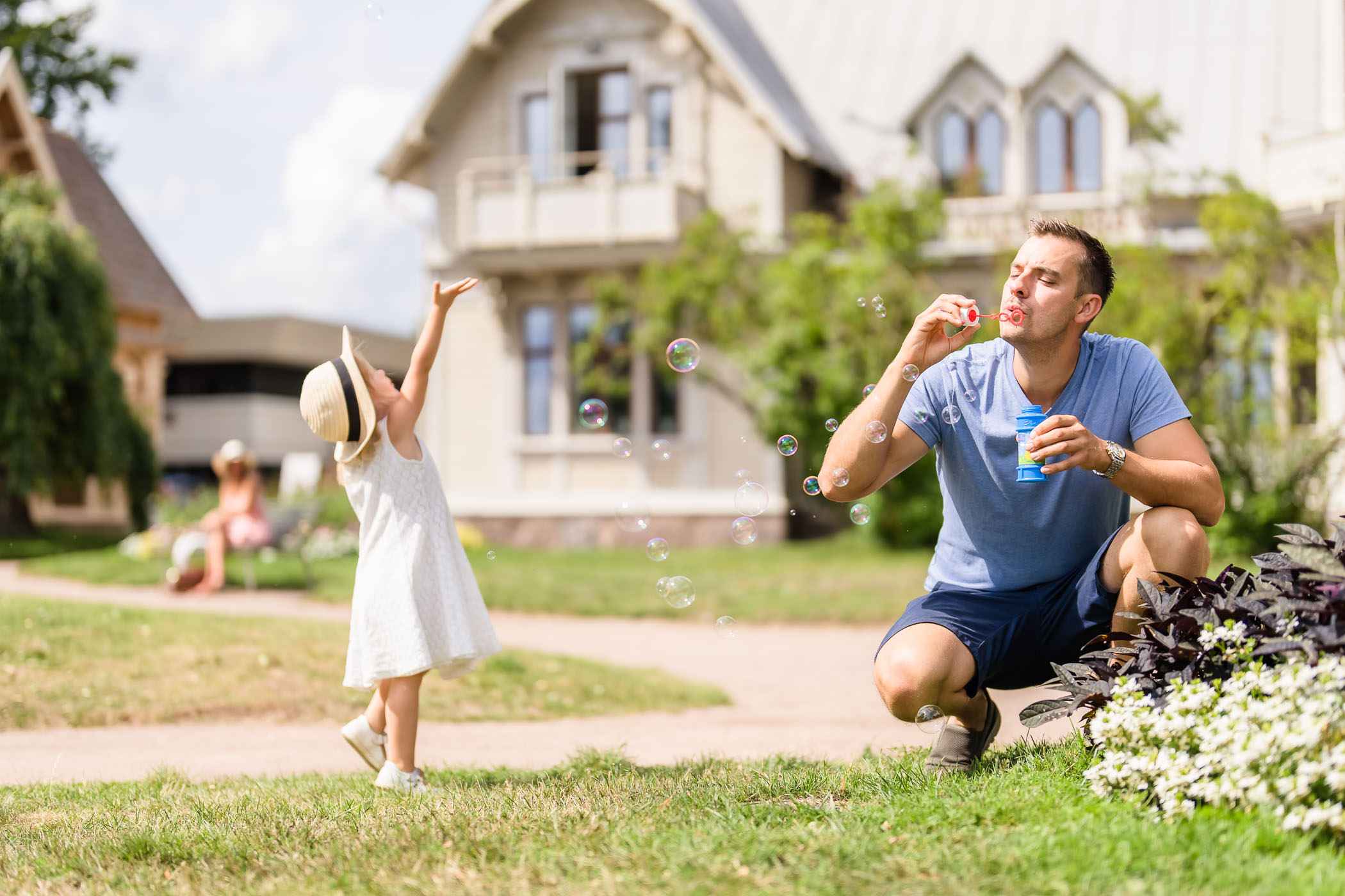 Far och dotter blåser såpbubblor i Hjo Stadspark. 