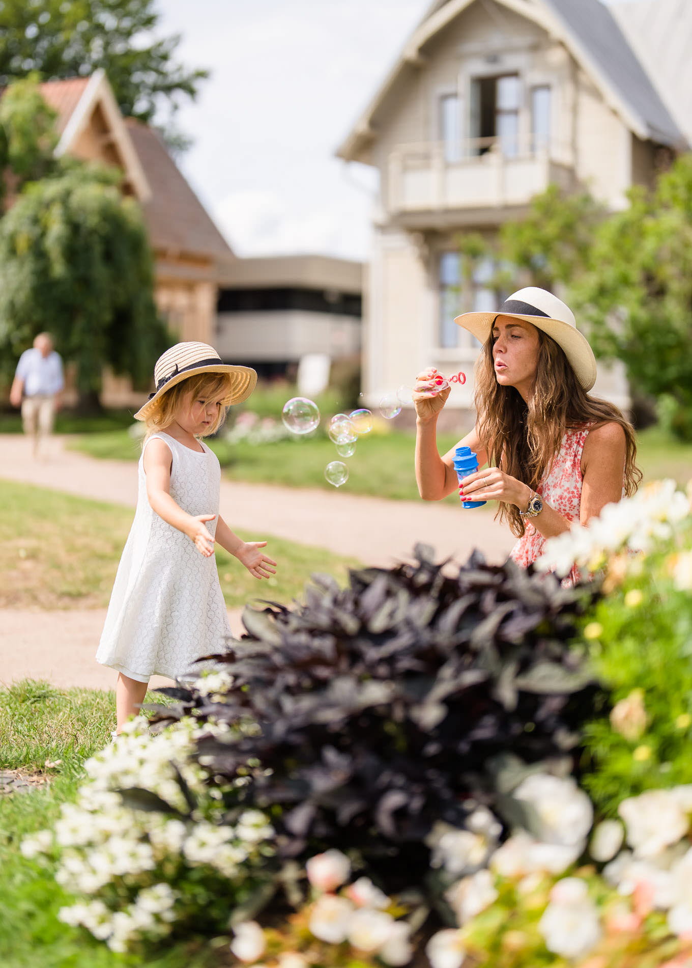 Mamma och dotter blåser såpbubblor i Hjo Stadspark. 