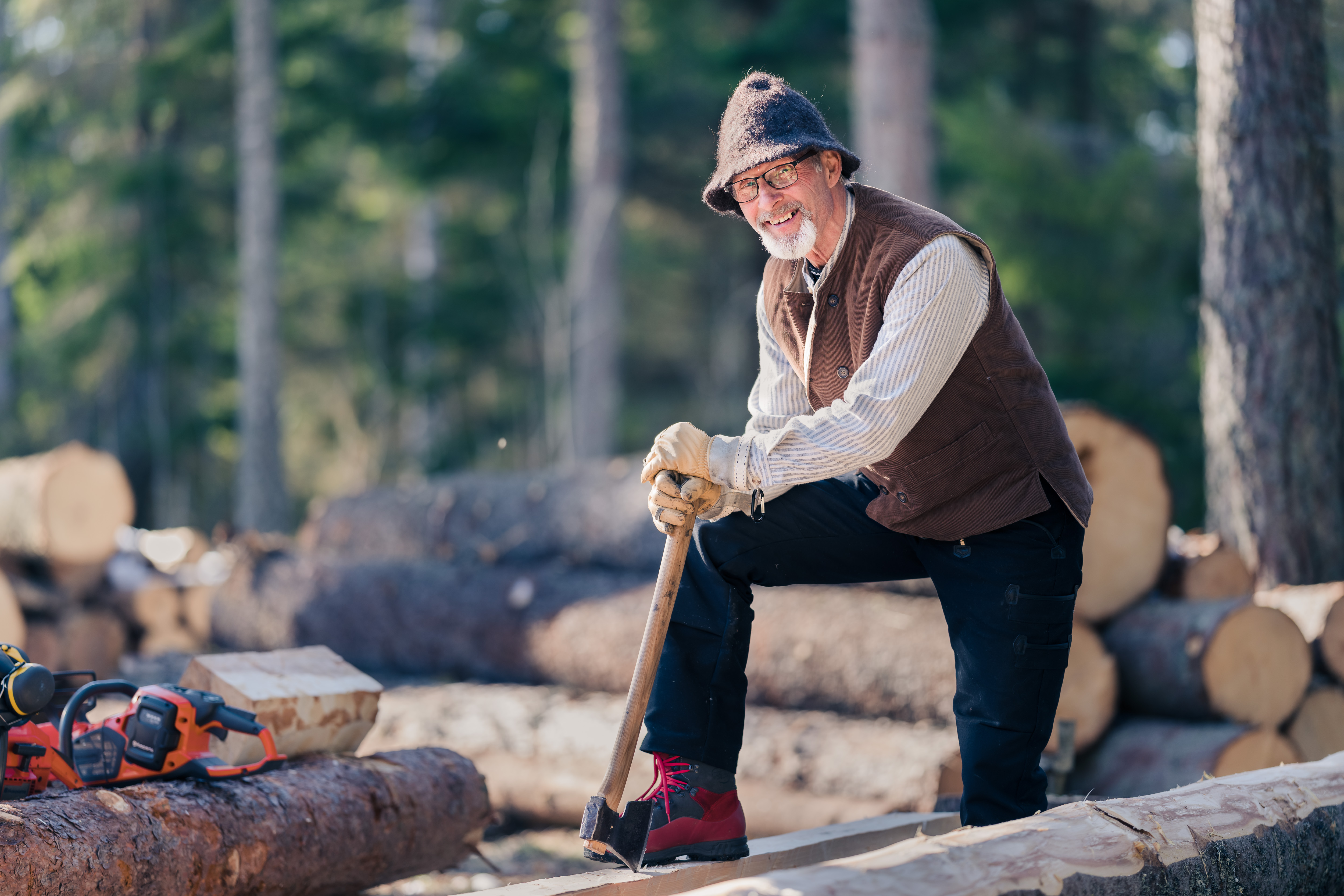 Man med yxa hugger timmer i skogen 