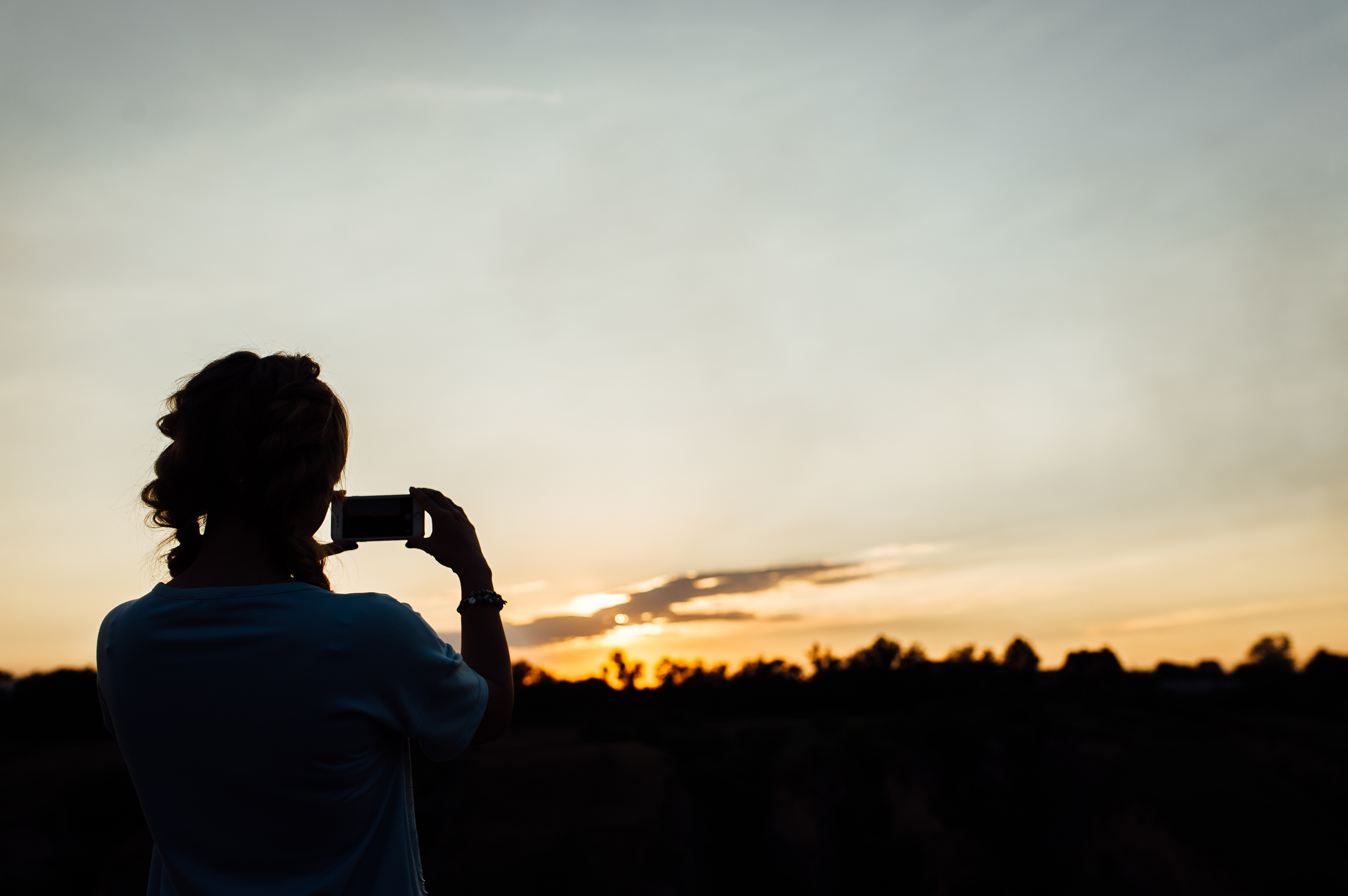 Kvinna som tar bild ute i naturen med sin mobil. 