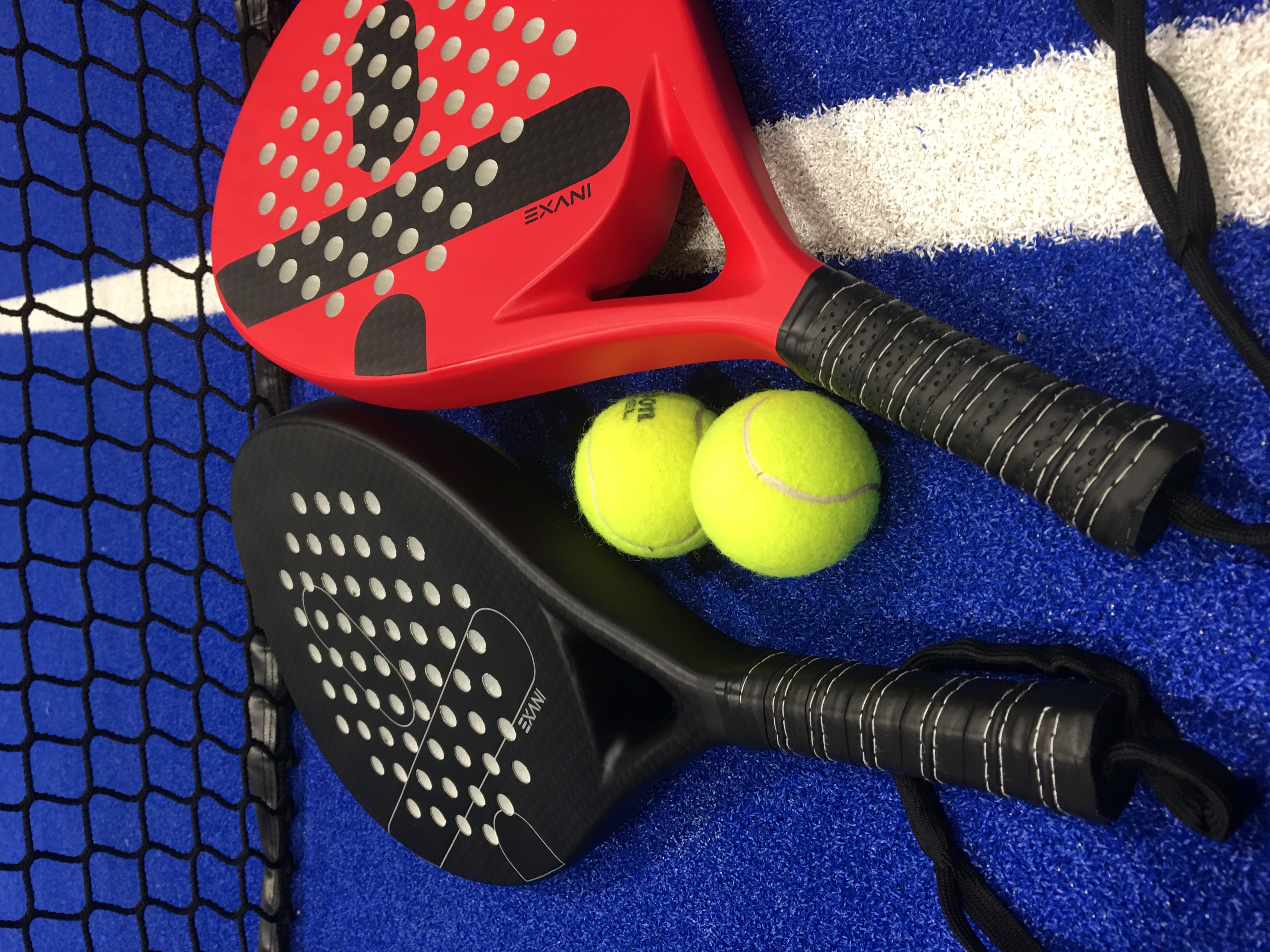Två padelrack och bollar på en padelbana.