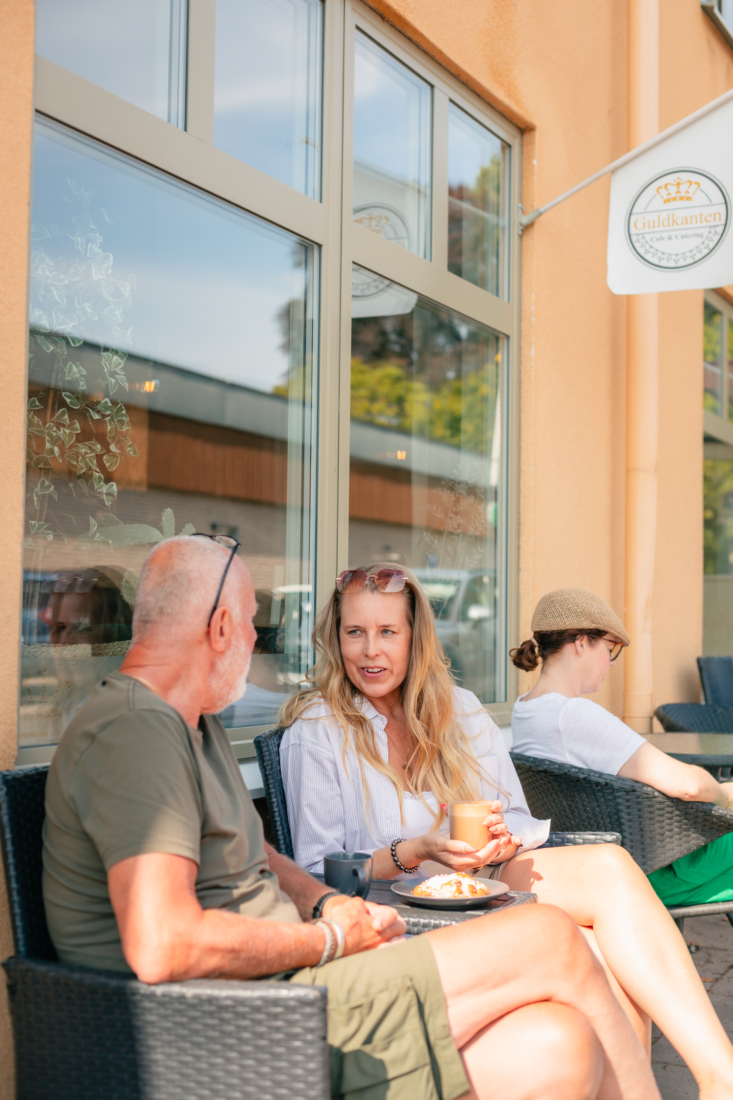 Tre personer sitter utanför Guldkanten och fikar